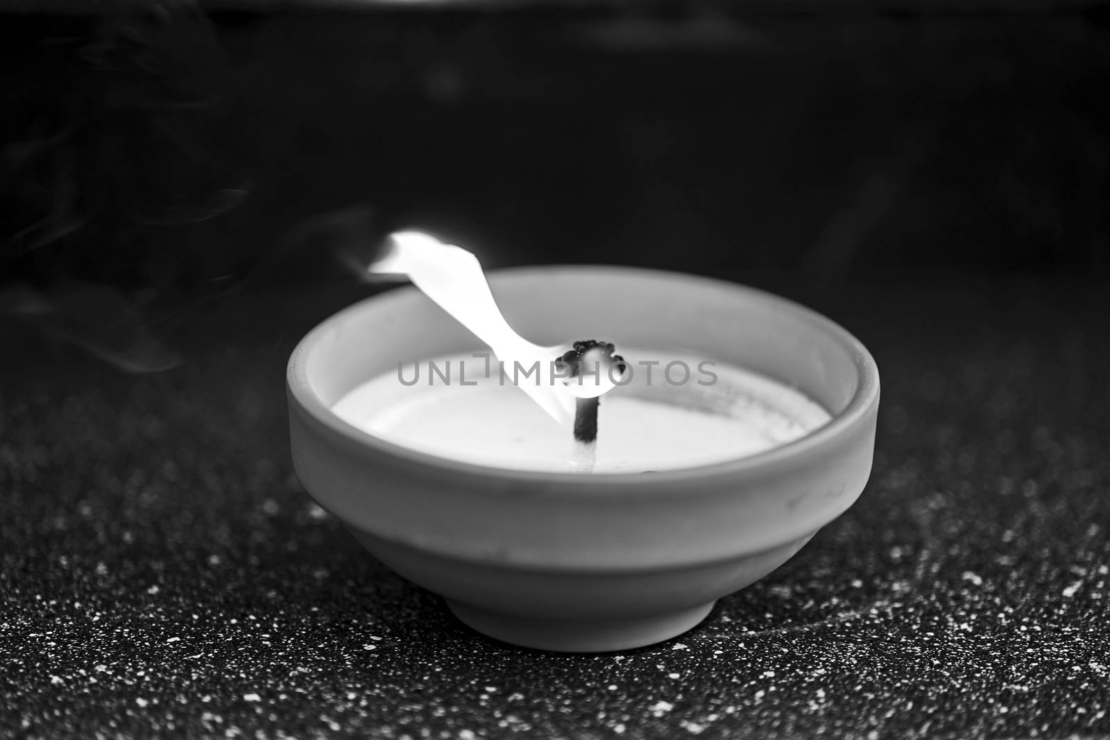 A candle burning on a grave in the cemetery of All Saints' Day in Poland, monochrome