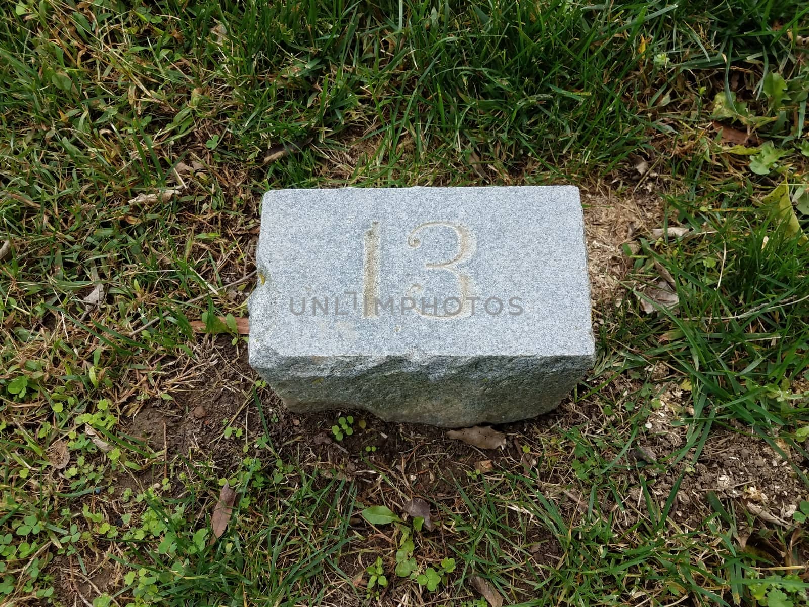 grey stone with number thirteen in green grass