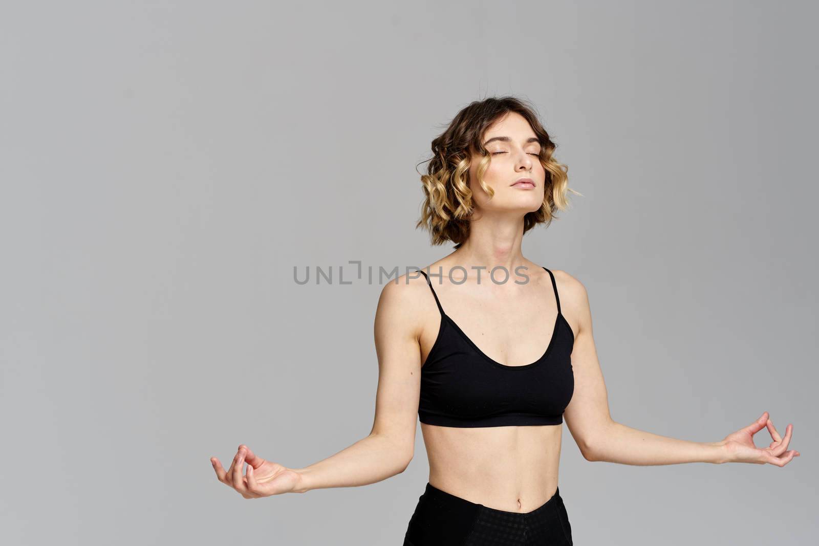 woman gesturing with her hands slim figure meditation sport gray background. High quality photo