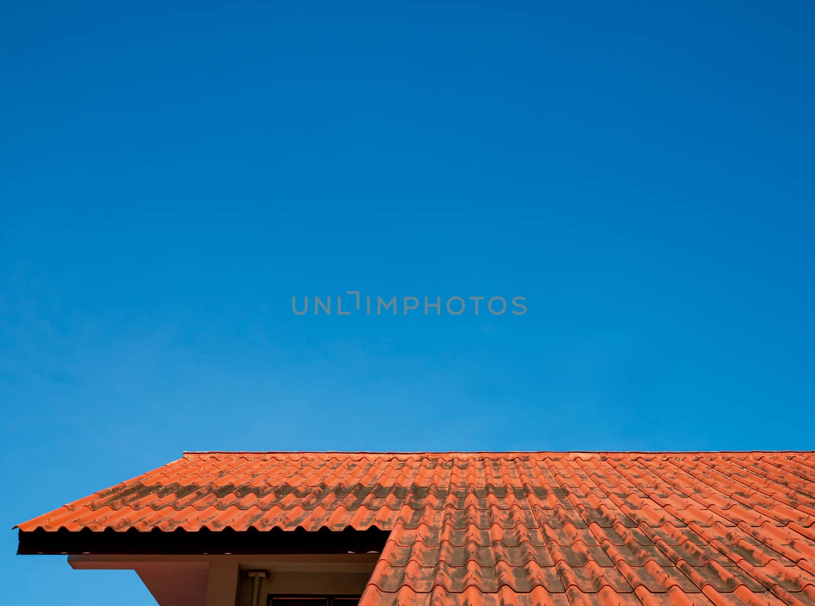 The roof tiles of the building have a background of blue skies o by Unimages2527
