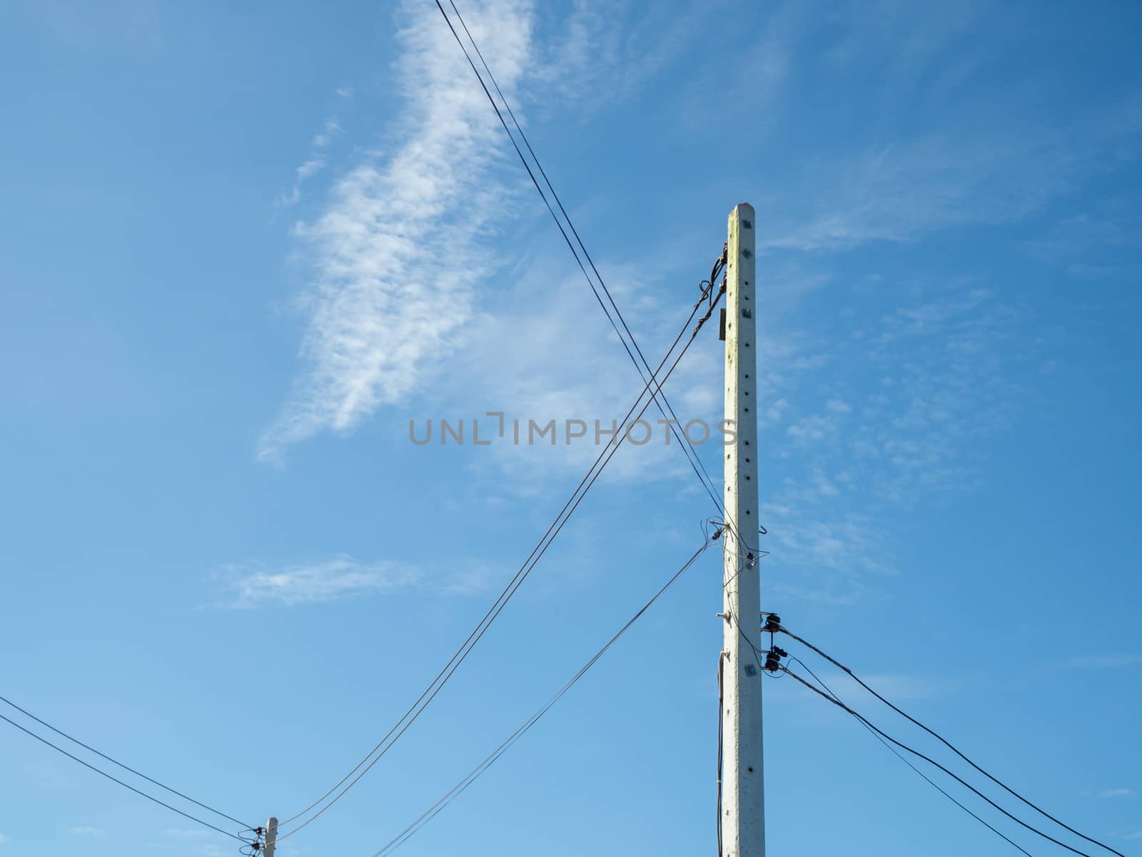Electric poles and wires in a bright blue sky background. by Unimages2527