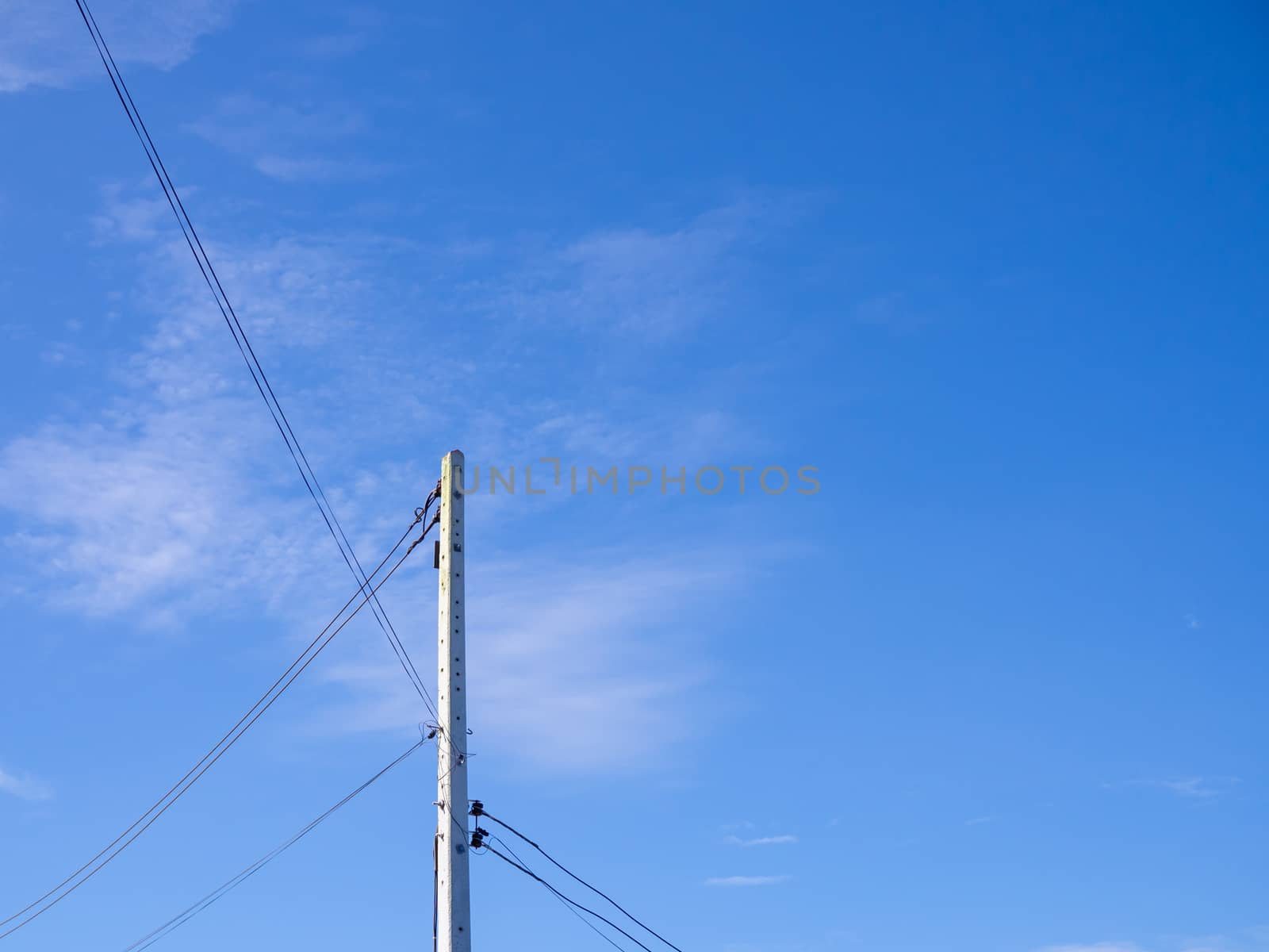 Electric poles and wires in a bright blue sky background.