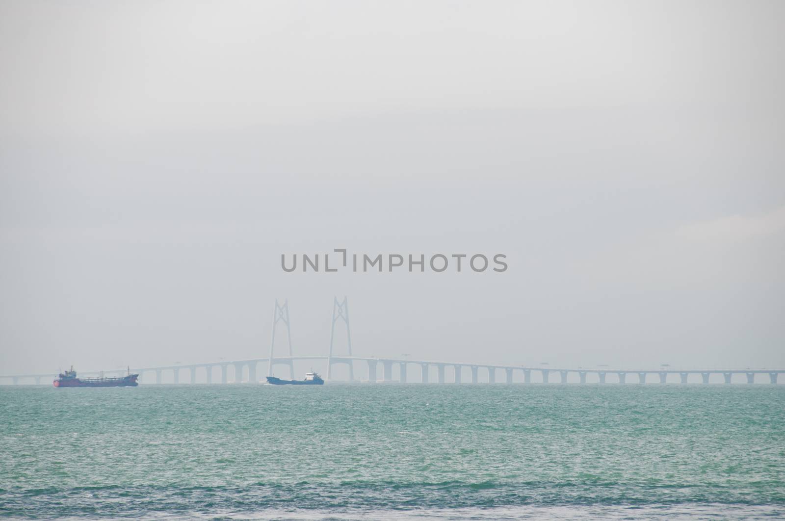 HONG KONG, HONG KONG SAR - NOVEMBER 18, 2018: Zuhai giantic mega bridge between China mainland and Hong Kong island. There are 2 ships floating near the bridge in hazy afternoon.