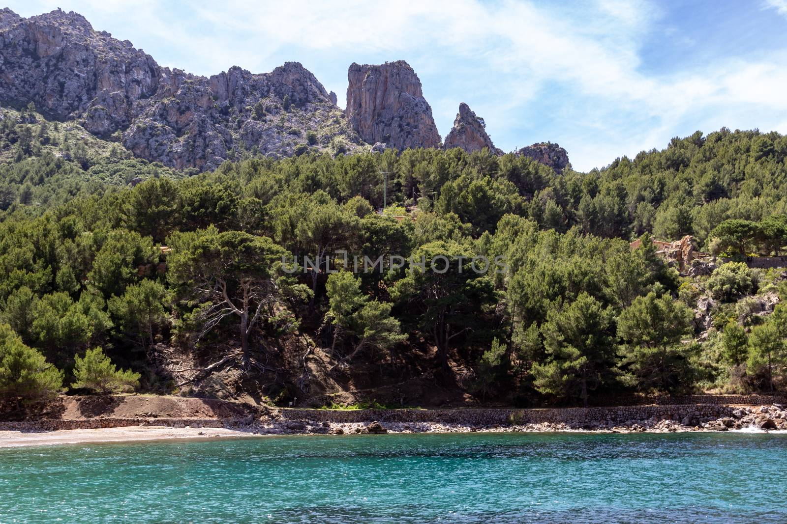 View on the coast at bay Cala Tuent on balearic island Mallorca, Spain on a sunny day with clear blue water and mountain range in background