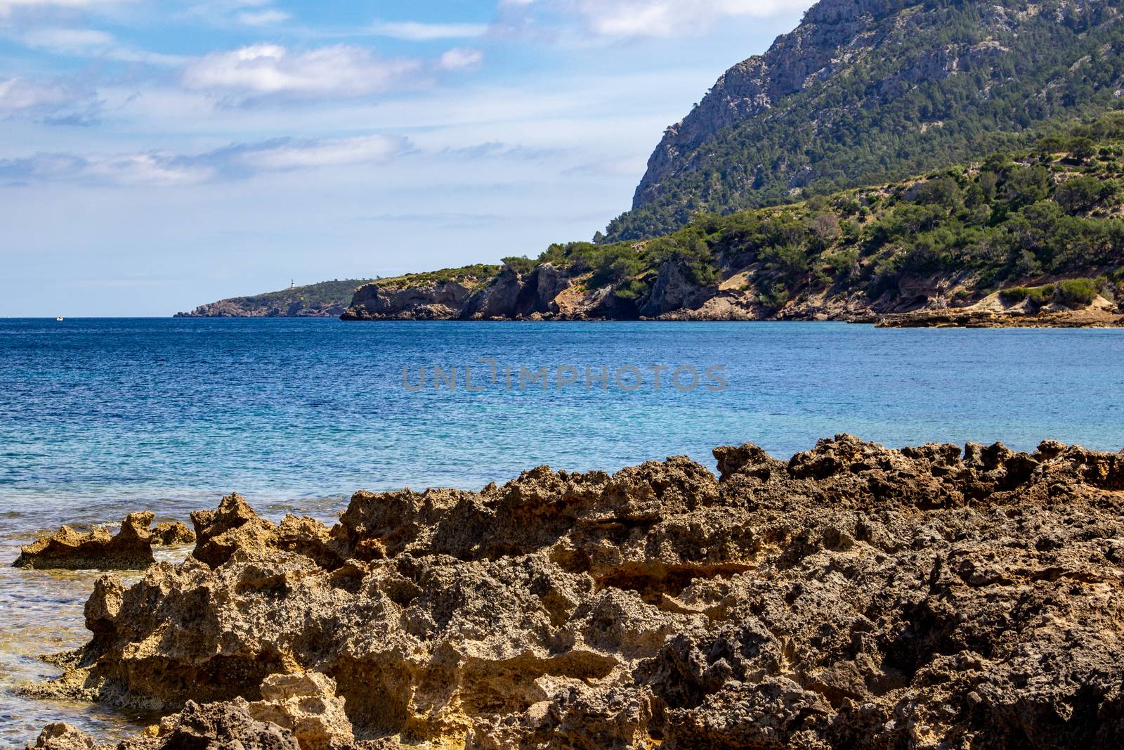 Bay on the peninsula La Victoria, Mallorca with ridge in the background, blue water and rocks in the sea