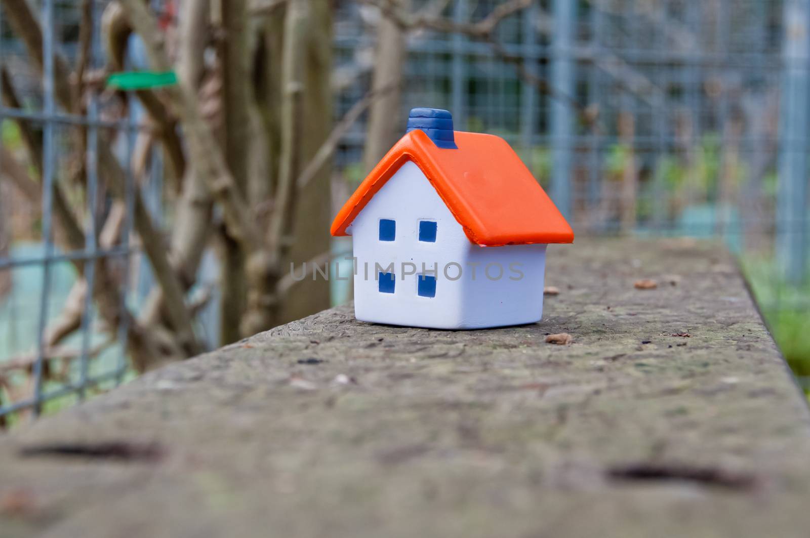 Miniature soft toy house on concrete fence