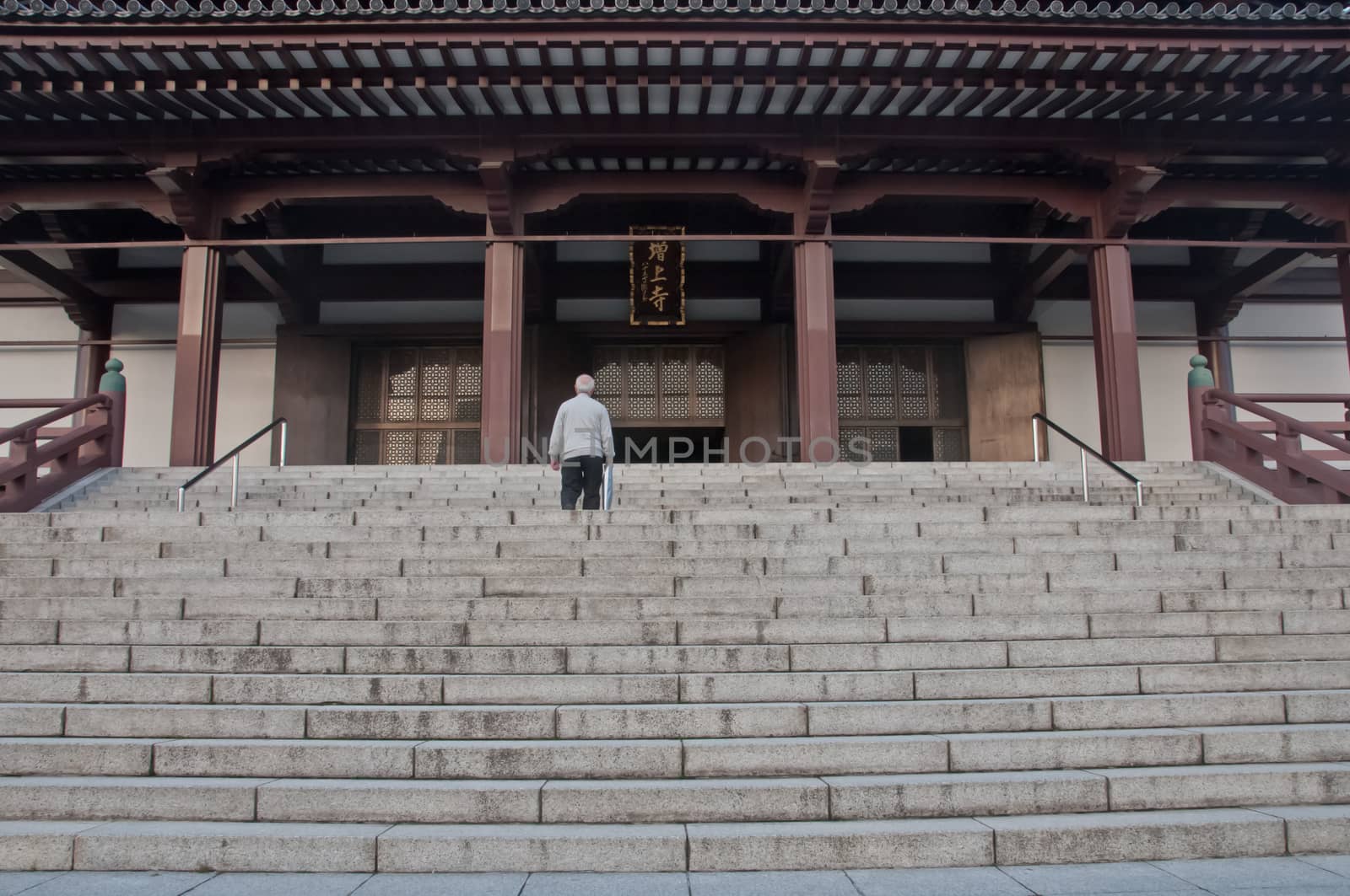 TOKYO, JAPAN - DECEMBER 1, 2018:  Zojo-ji Buddhist temple. This is a famous temple which has the oldest wooden main gate in Tokyo built from 1622. There is an old man stands to pray in front of the main temple hall.