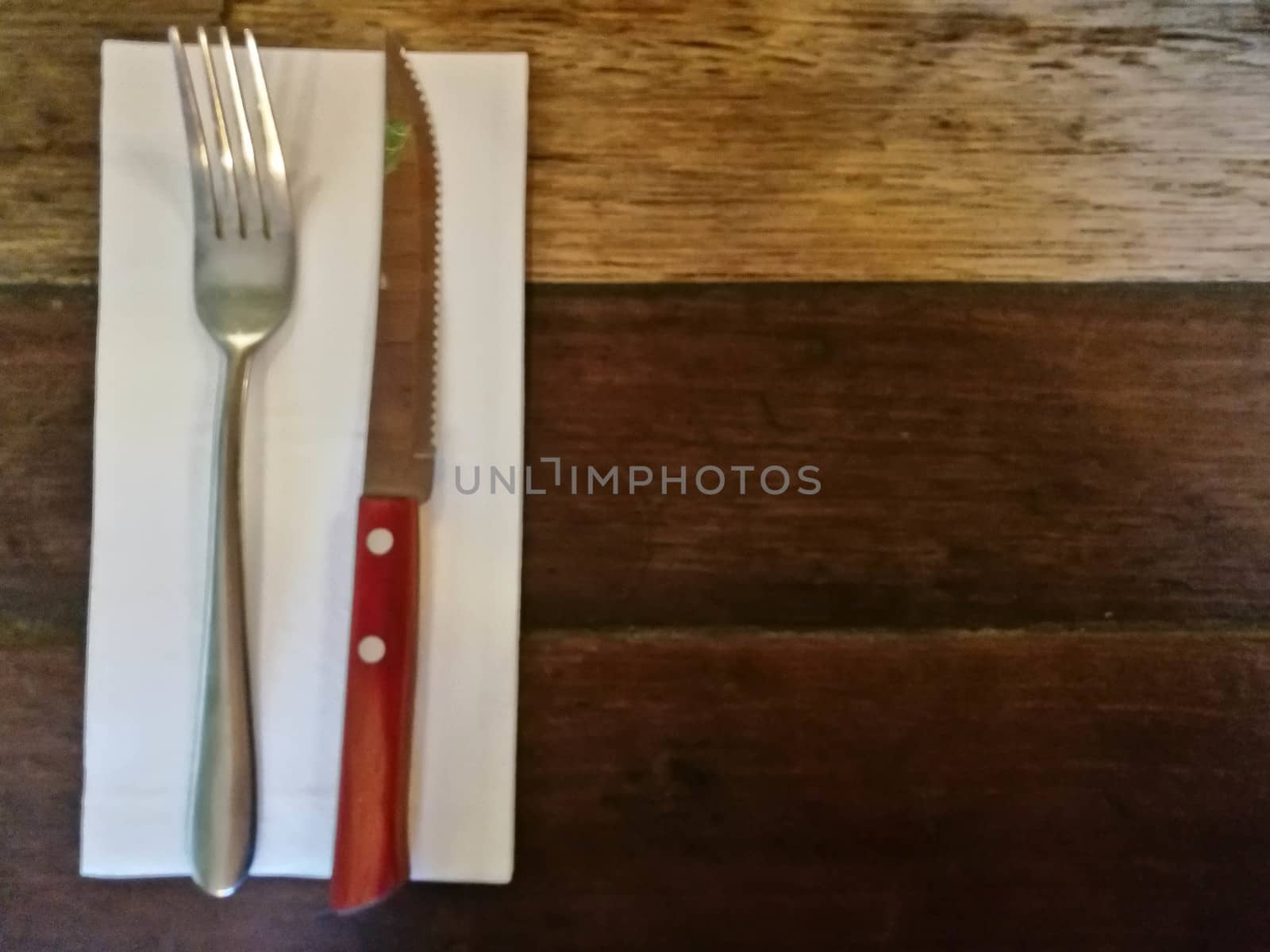 Top view of silver fork and knife on tissue paper on wooden classic table