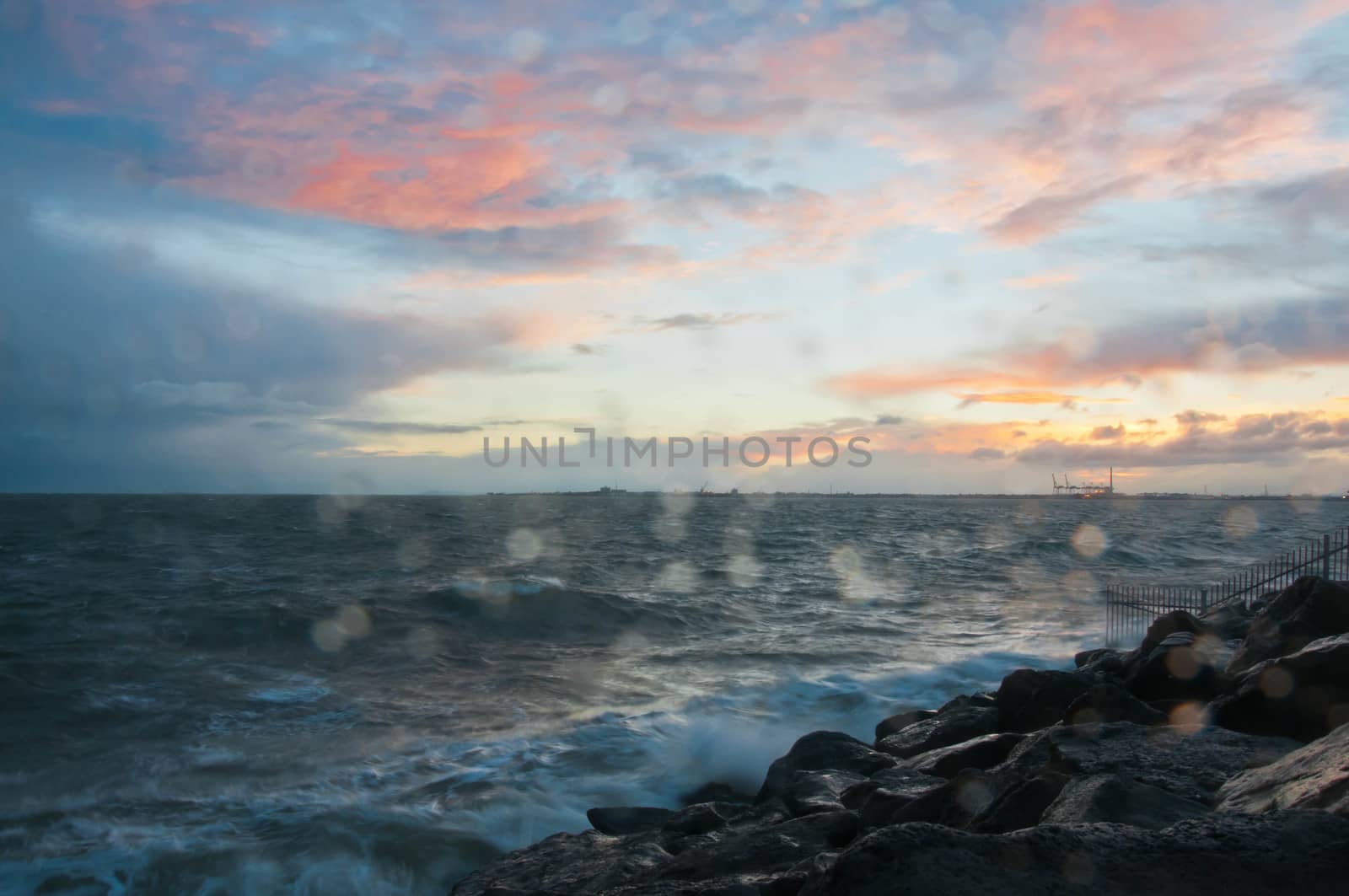 Dramatic splashing ocean wave in the evening with twilight sky in Winter at breakwater at St Kilda pier in Melbourne Australia