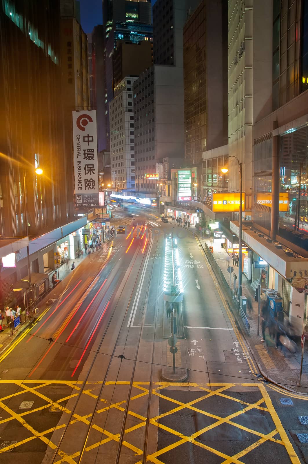 HONG KONG, HONG KONG SAR - NOVEMBER 17, 2018: Light blur motion scene of tram and traffic in central Hong Kong at night. There are many pedestrians on the street.