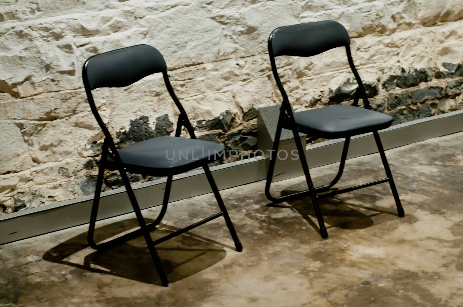 Two modern black chairs in a strong rock prison cell by eyeofpaul