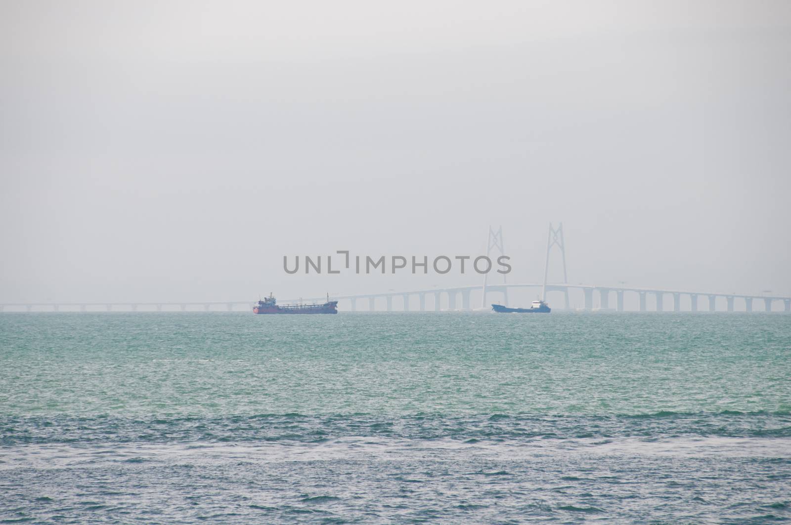 HONG KONG, HONG KONG SAR - NOVEMBER 18, 2018: Zuhai giantic mega bridge between China mainland and Hong Kong island. There are 2 ships floating near the bridge in hazy afternoon.