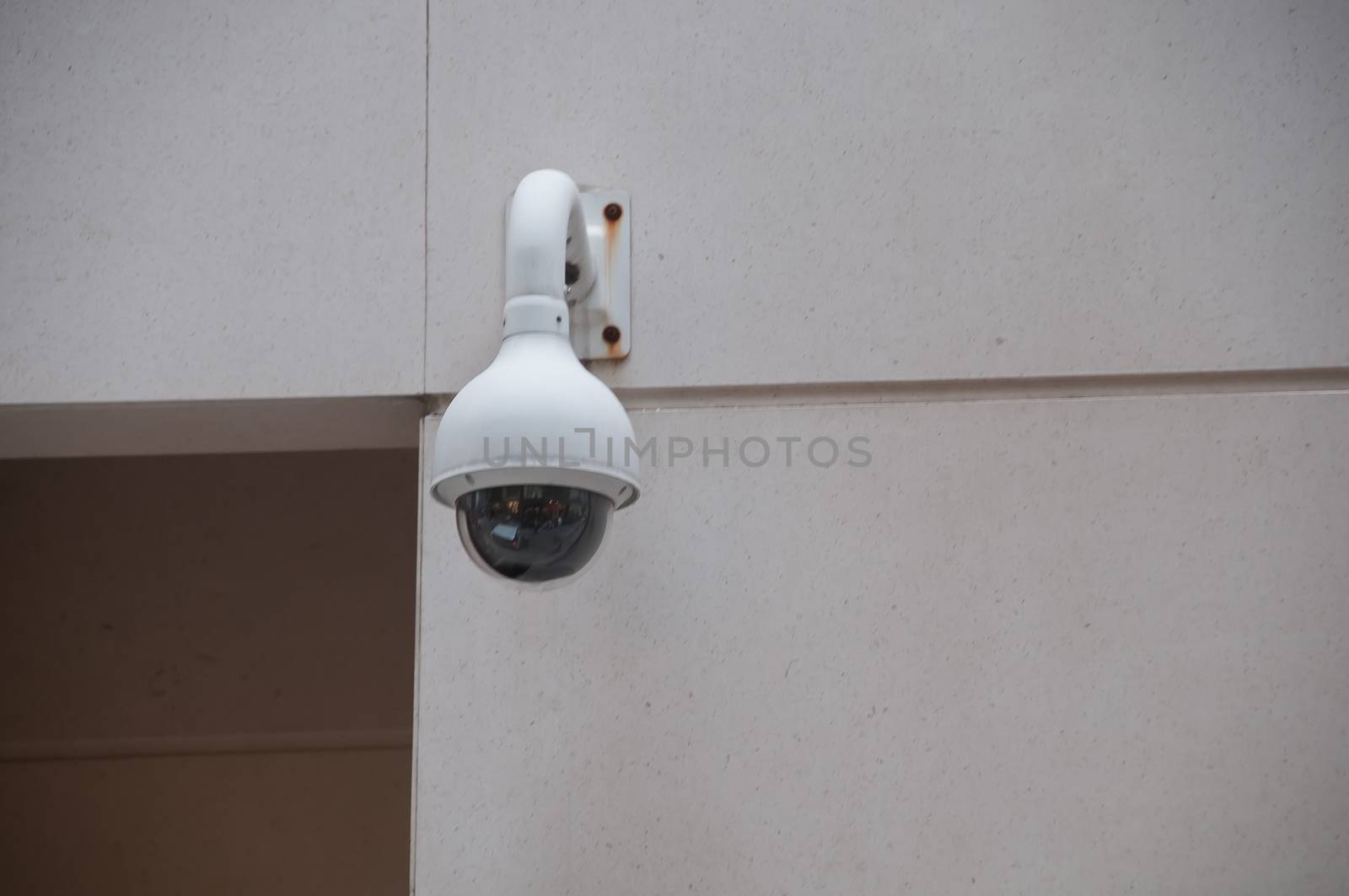 Security CCTV dome camera attached to a white wall near the door by eyeofpaul