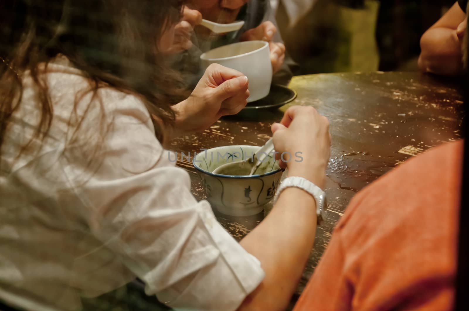 Lady sits and eats famous hot and cold sweet dessert soup in a round table with her friend in Hong Kong restaurant cafe