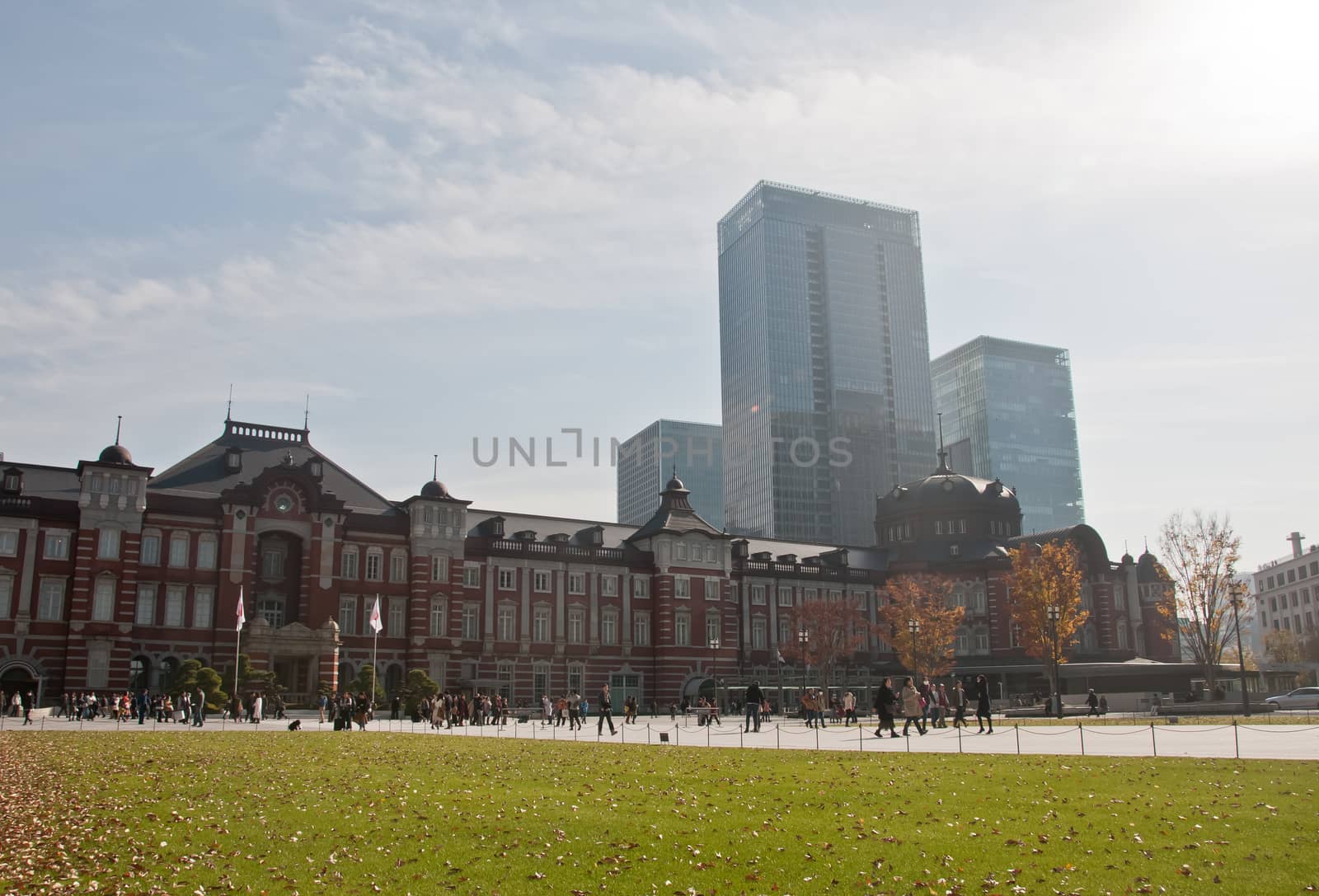 TOKYO, JAPAN - DECEMBER 1, 2018:  Tokyo Station railway building with Ginkgo yellow foliage leaves trees in late Autumn. There are many people walk on the street in front of the station.