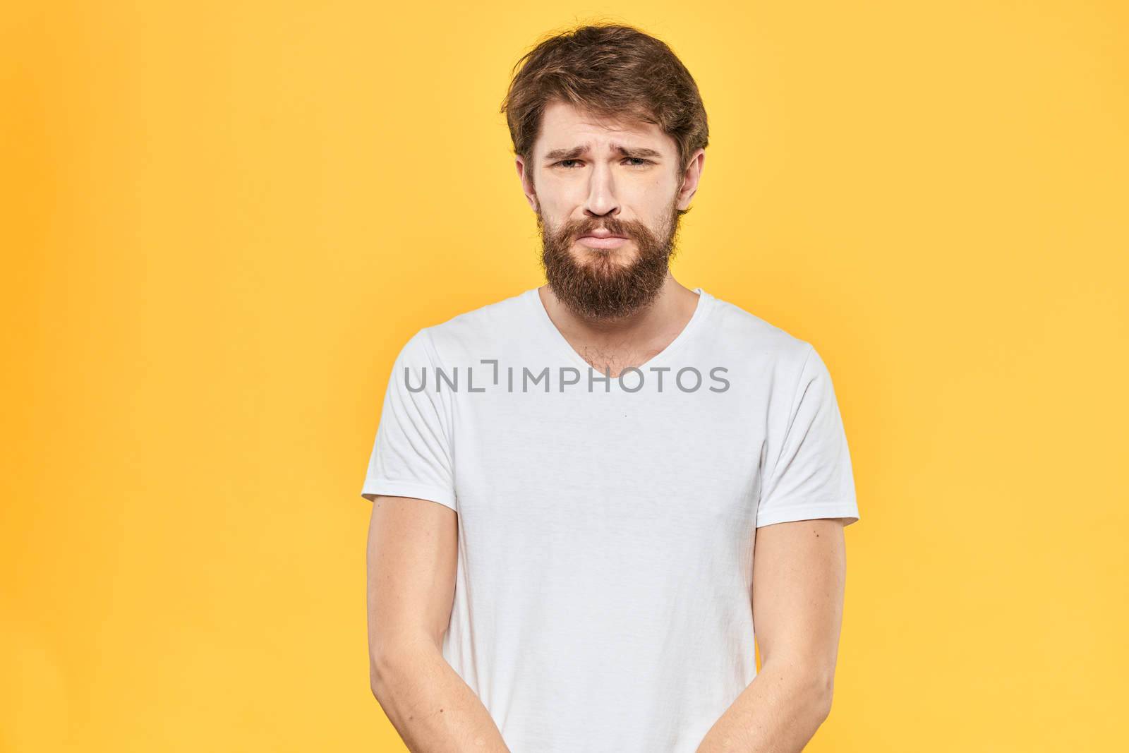 Bearded man emotions gestures with hands facial expression white t-shirt yellow background by SHOTPRIME