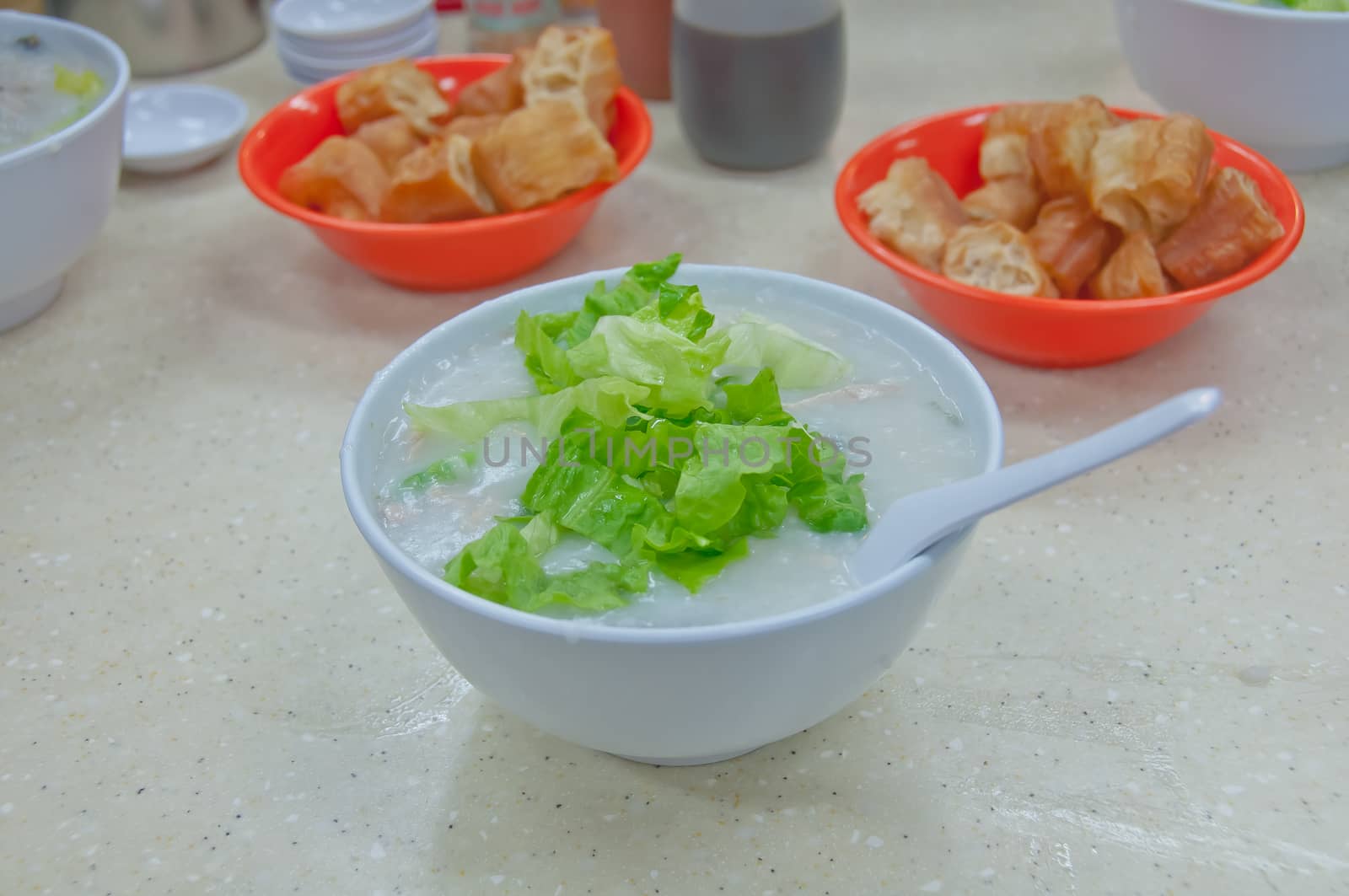 Fresh plain congee rice porridge topping with green shallot and Chinese donut in Hong Kong