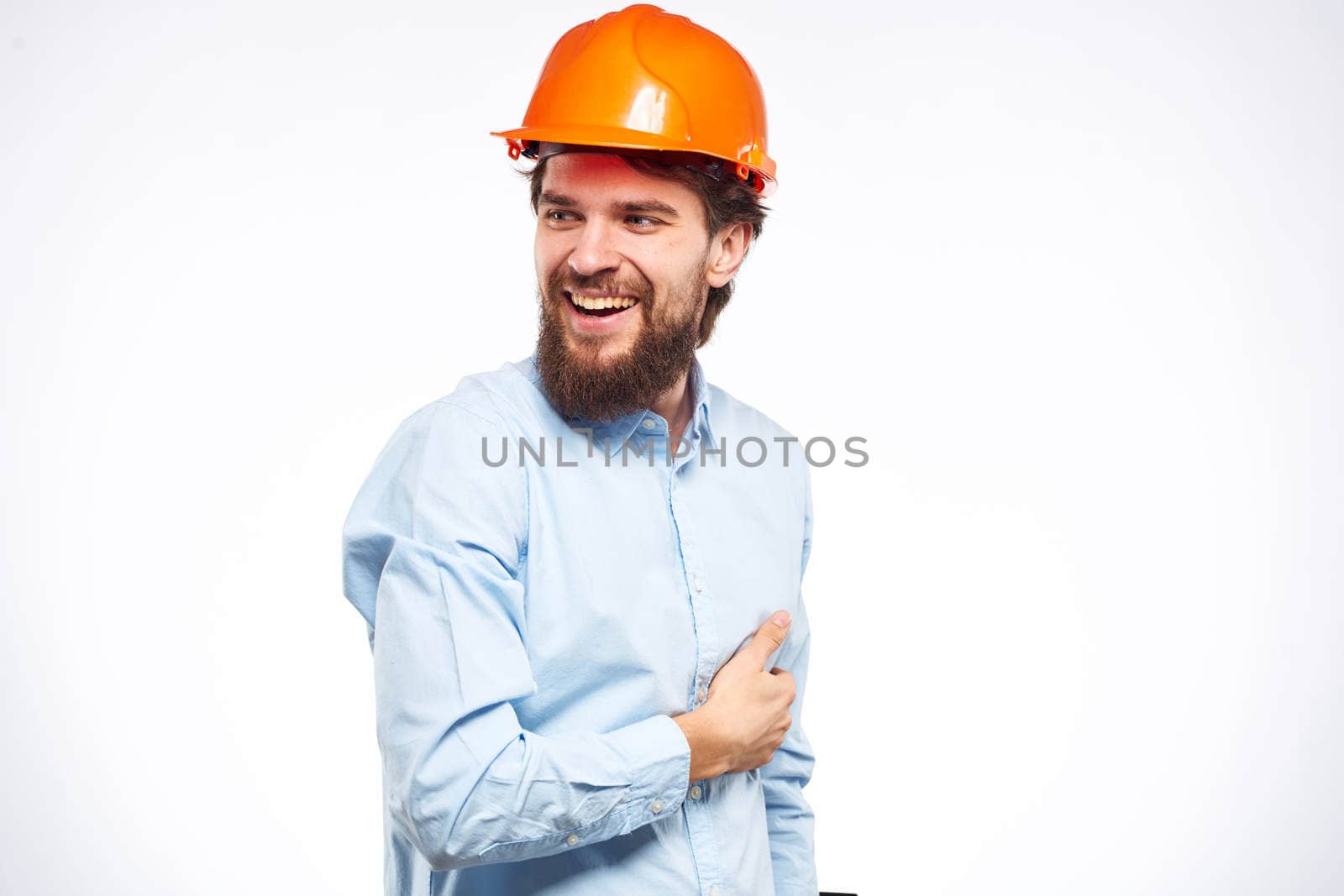 Cheerful man orange hard hat work industry professional lifestyle light background. High quality photo