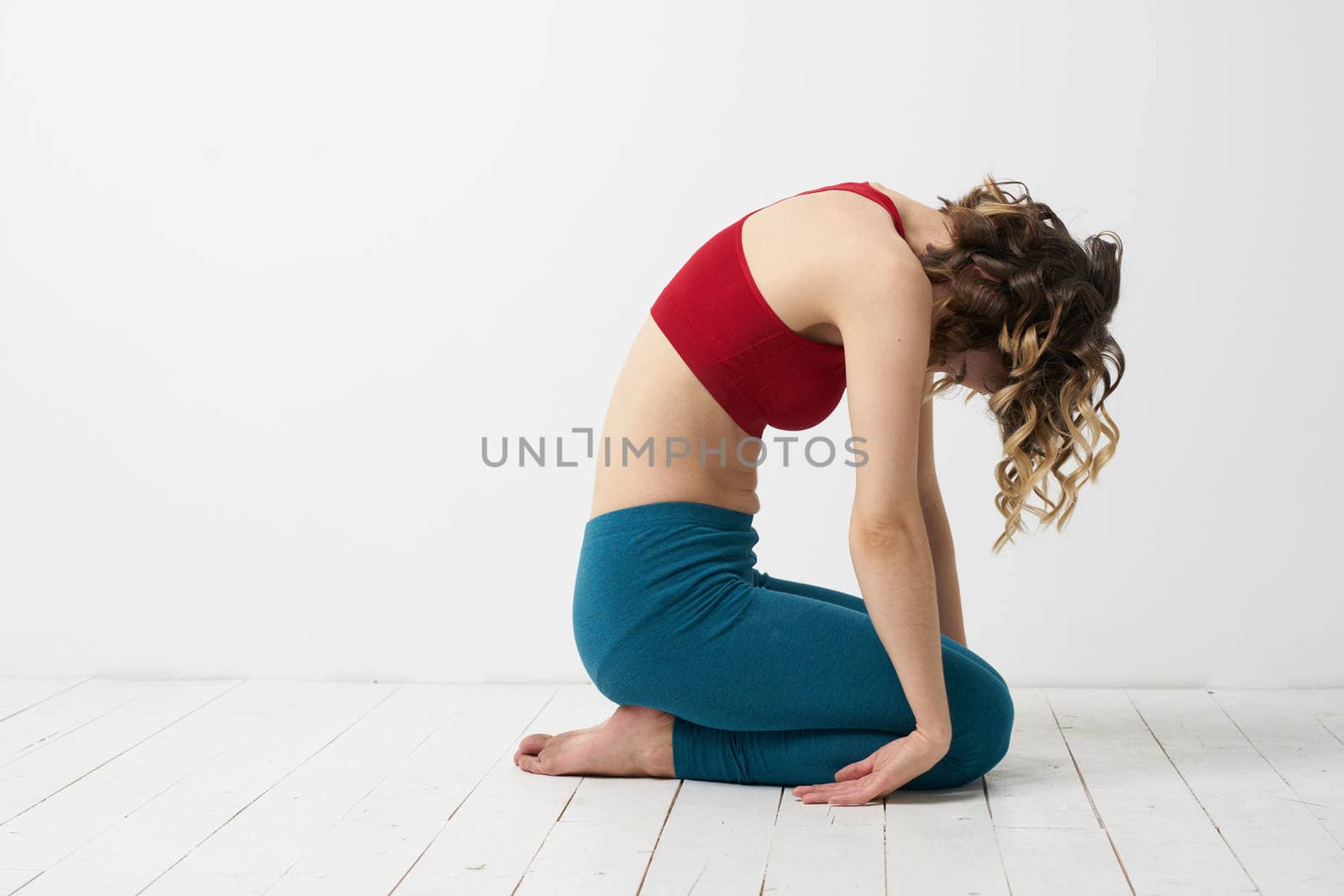 the girl is engaged in yoga on a light background Red T-shirt gesticulating with his hands. High quality photo