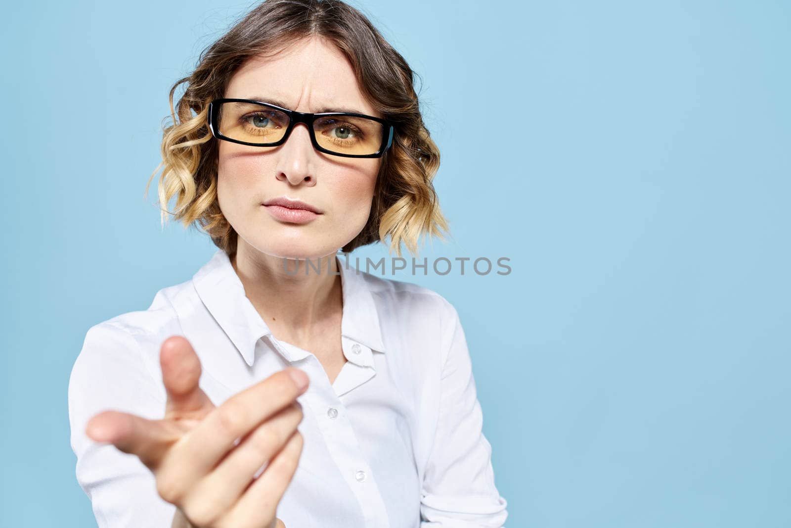 Business woman in a light shirt on a blue background gestures with her hands emotions model work. High quality photo