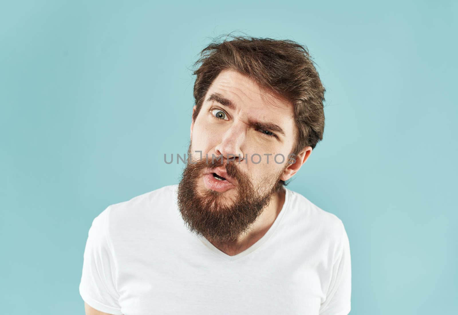 Aggressive man with a beard on a blue background cropped view. High quality photo