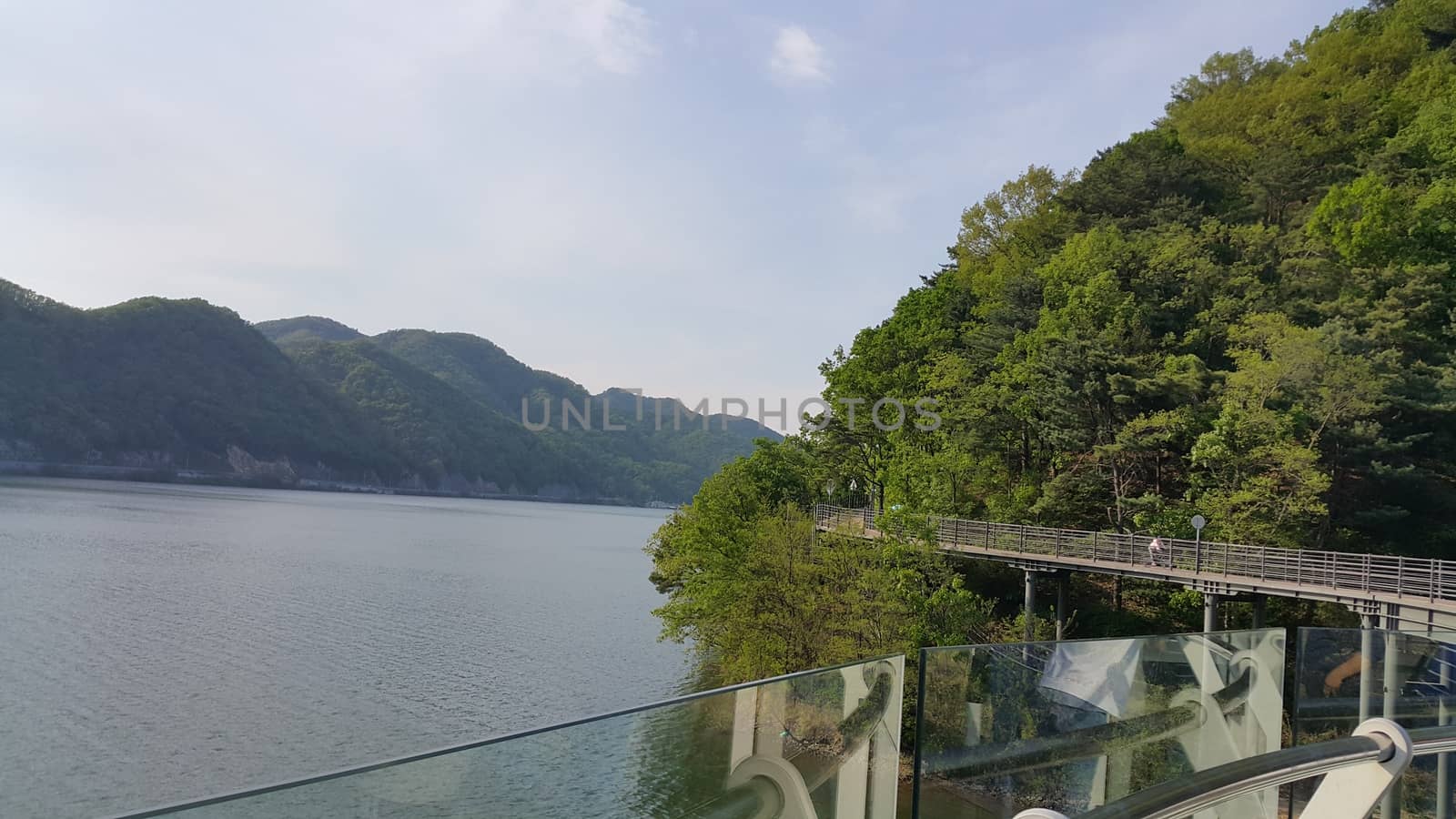 View of beautiful scene of river water and green trees on large hills on a sunny day with blue sky in background. A lovely landscape with breathtaking view over the horizon .