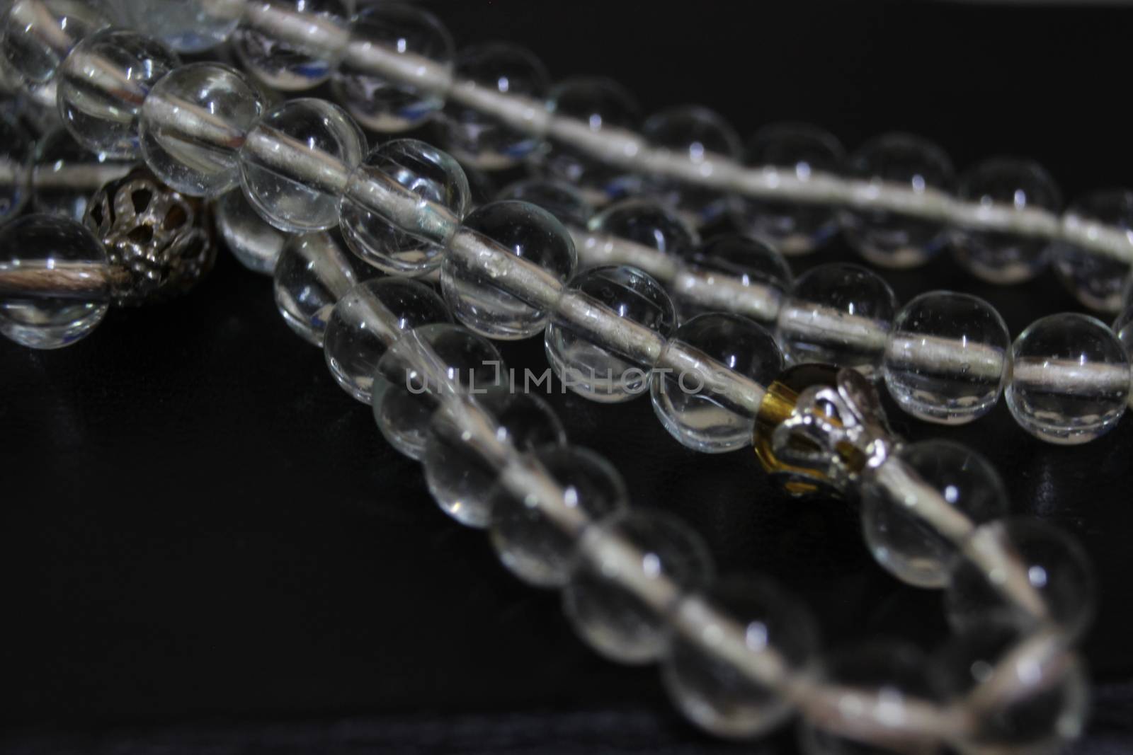 Macro photograph with selective focus of glass shiny prayer beads or rosary with copy space for text. Religion concept of ramadan or Eid for muslims.