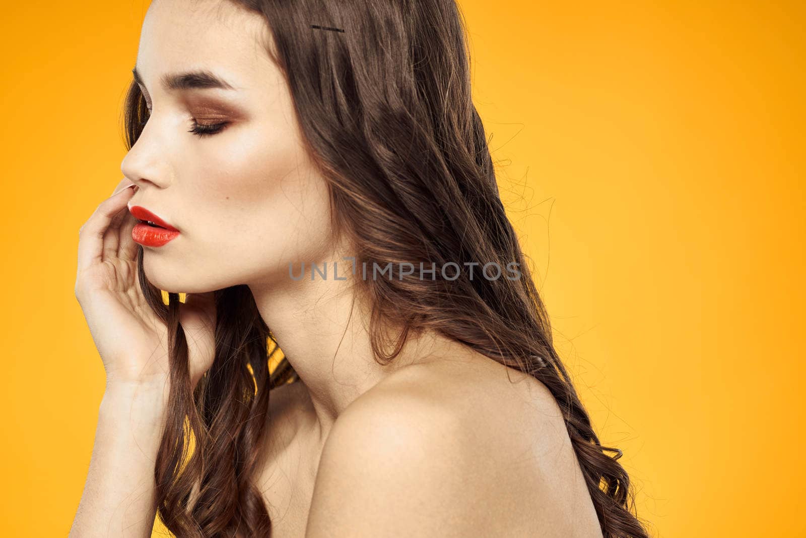 beautiful brunette red lips bare shoulders skin care yellow background. High quality photo