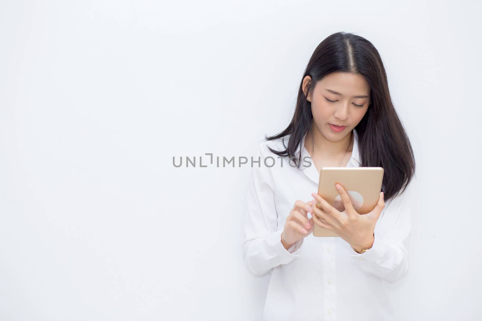 Beautiful portrait young asian woman using tablet computer cement background, businesswoman sitting looking tablet, communication concept.