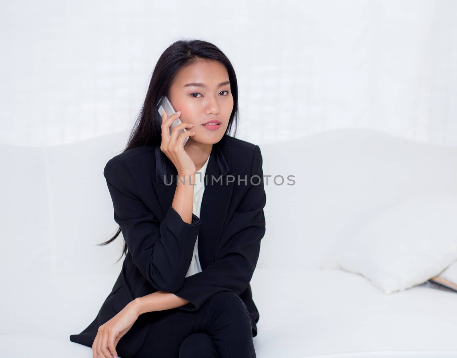 Beautiful young asian woman talking phone and smile in the livin by nnudoo