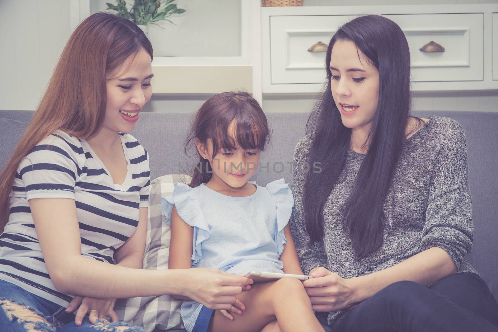 Mother, Aunt and kid having time together lerning with using tablet at home with relax and happy on couch, education and lifestyle concept.