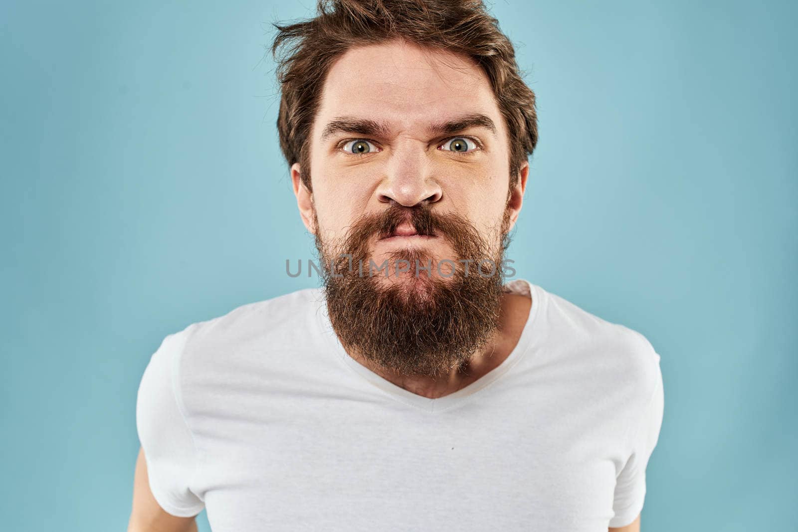 Man with disgruntled facial expression gesturing with hands studio lifestyle blue background by SHOTPRIME