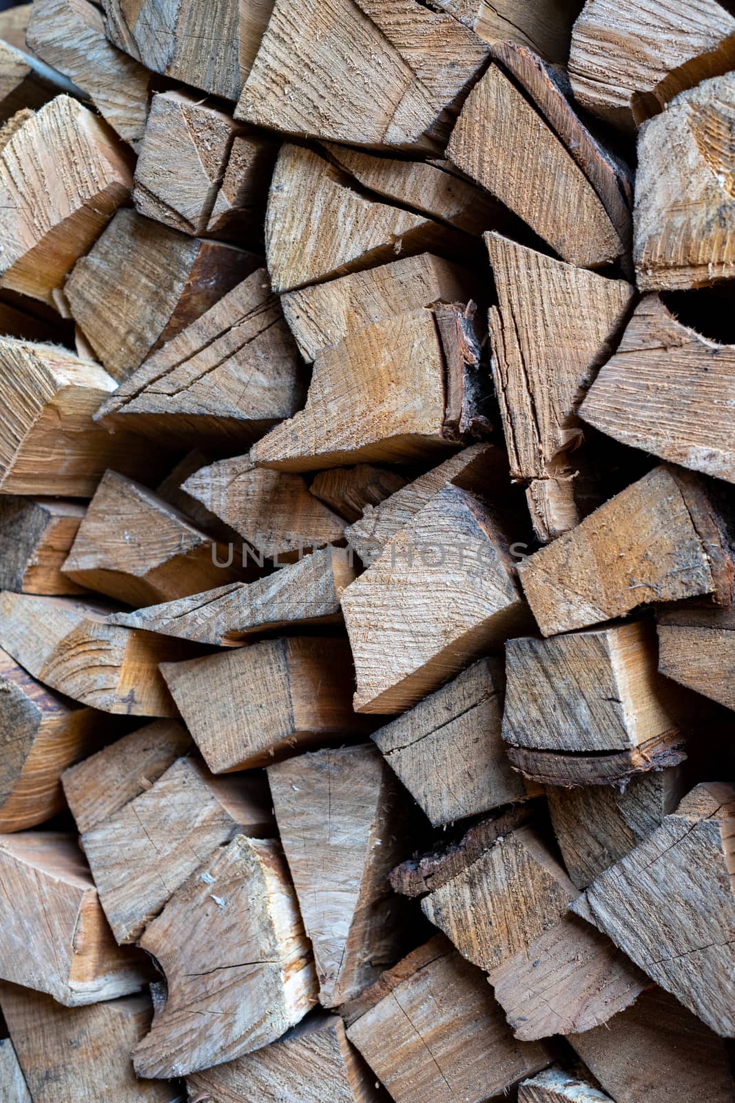 Firewood is stacked one on top of the other. Background texture. Vertical photo.