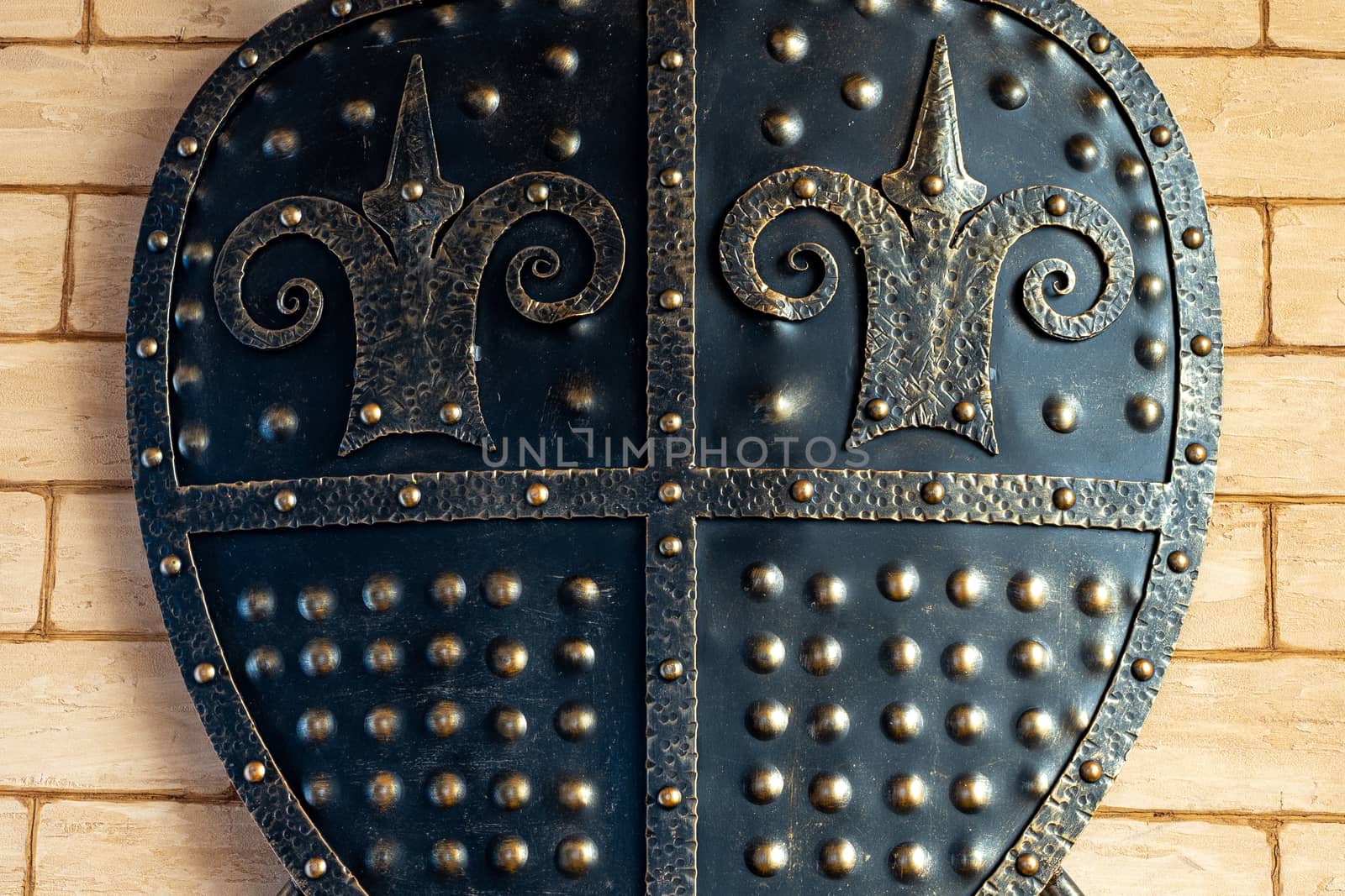 The interior design. A metal shield hangs on the wall as a decoration. Iron shield close up