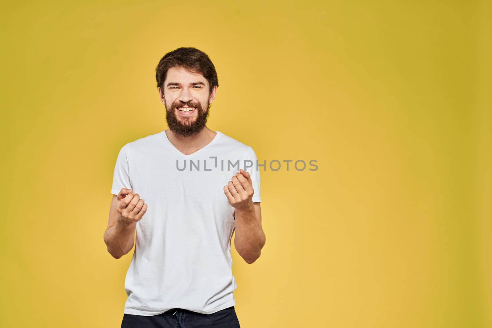 Man gesturing with hands emotions lifestyle white t-shirt yellow isolated background. High quality photo