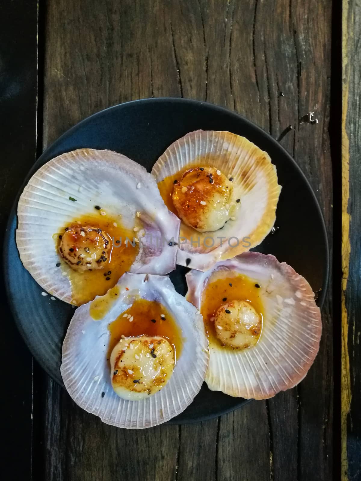 Giant grilled fresh Tasmanian scallops with fresh butter on blac by eyeofpaul