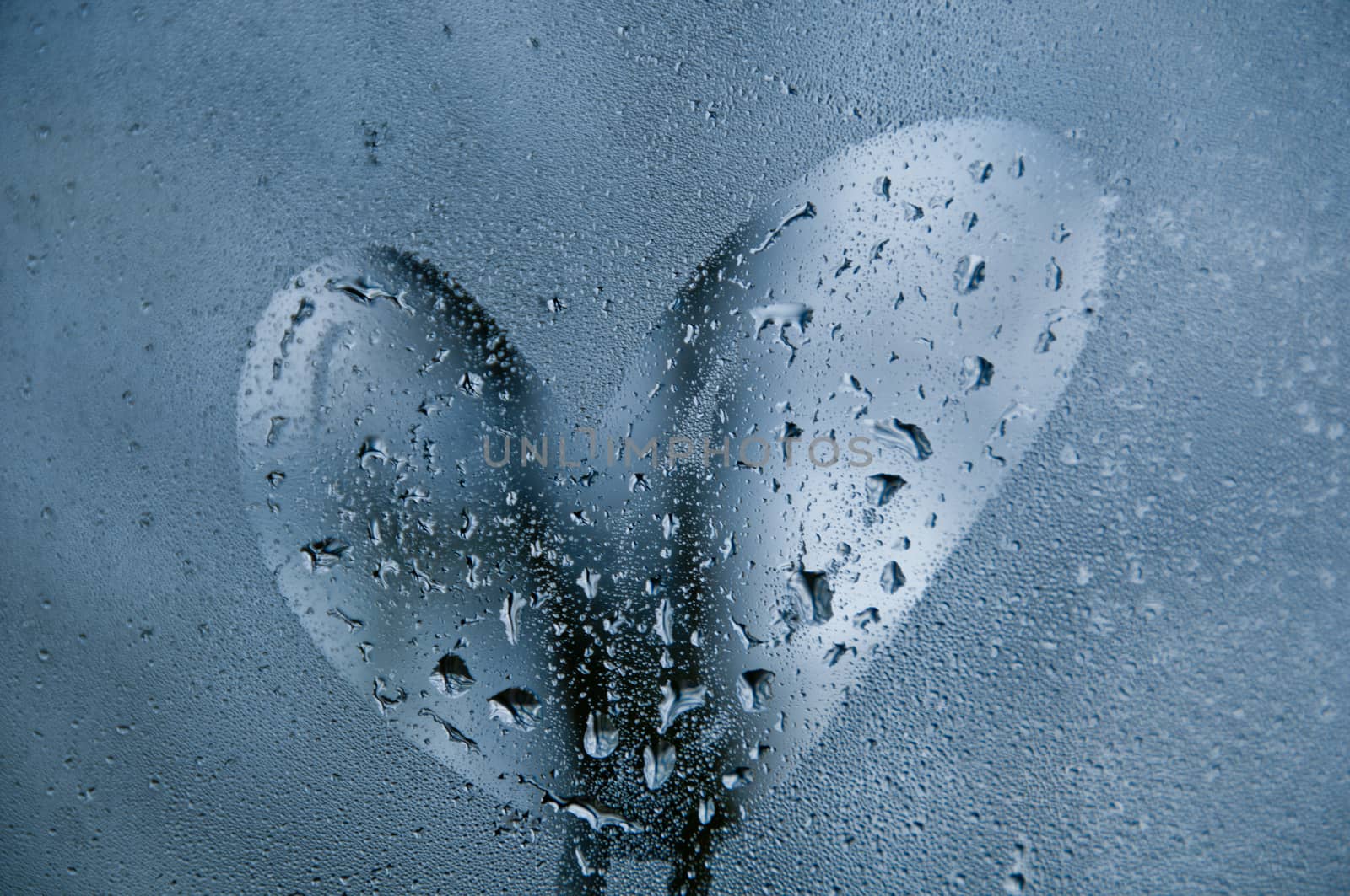 Heart shape on droplet window of cold misty morning