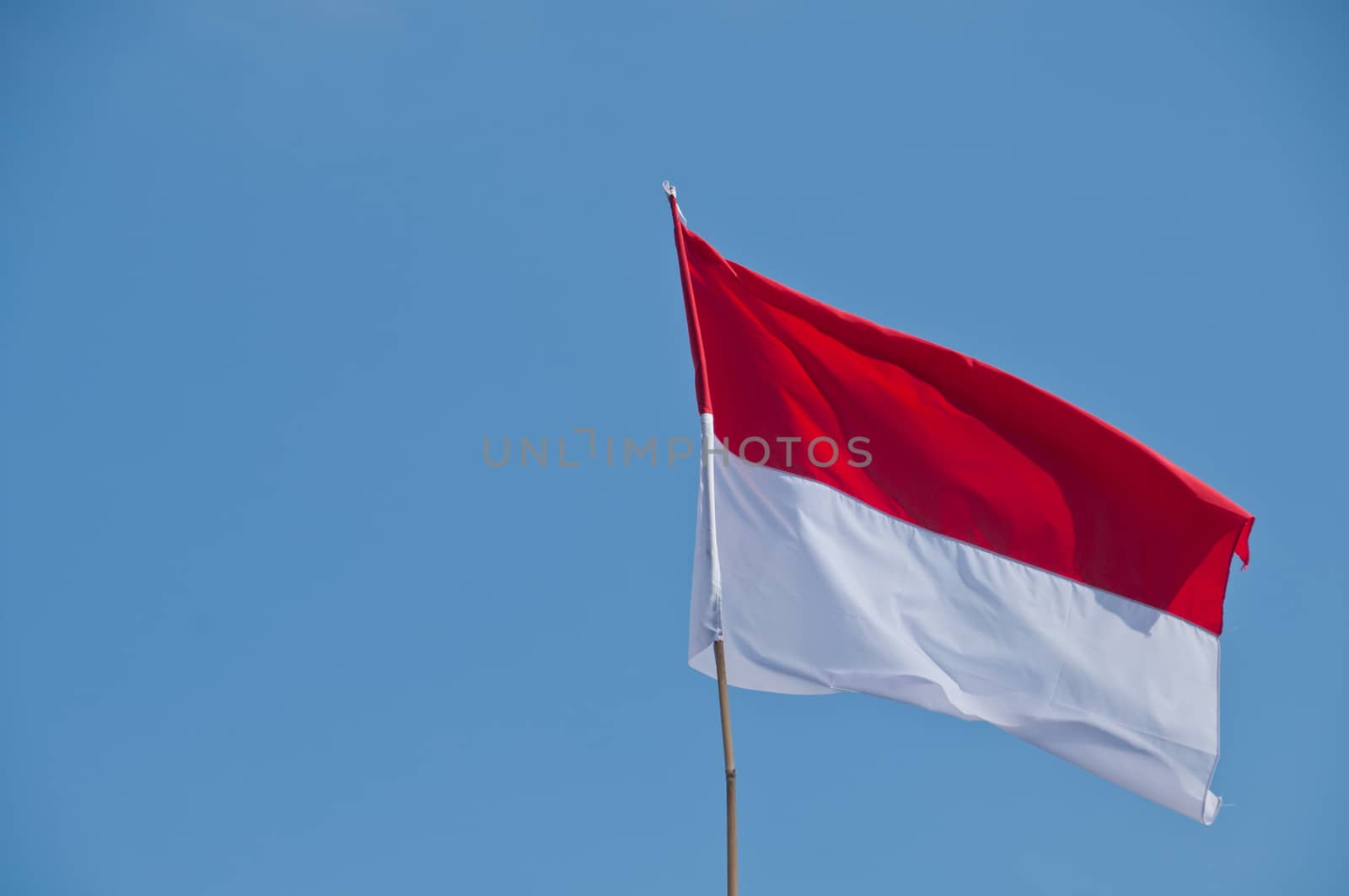 White and Red national flag of Indonesia with blue sky by eyeofpaul