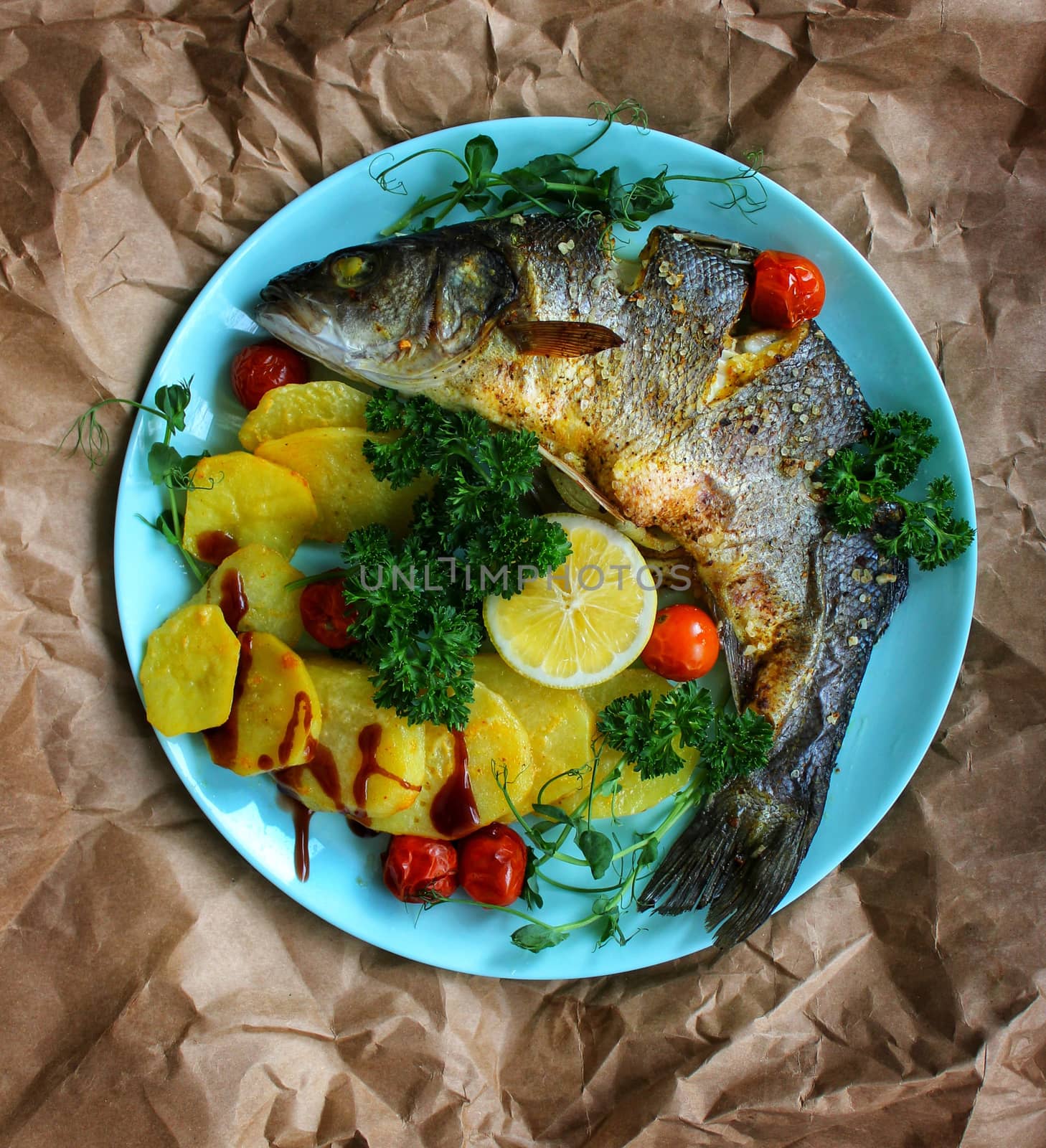 Fried fish close up with potatoes laid out on a plate on a crumpled paper background