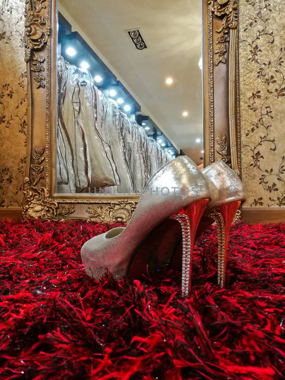 Silver shiny high-heeled shoes stiletto on red carpet in wedding studio