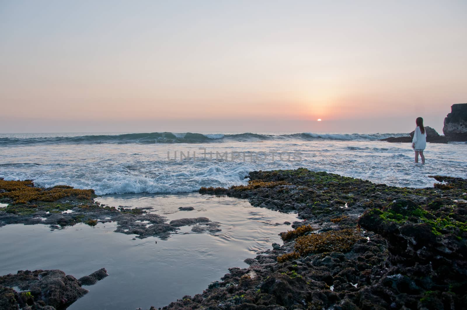 A lady standing at Sunset scene at Tanah Lot beach in Bali Indonesia