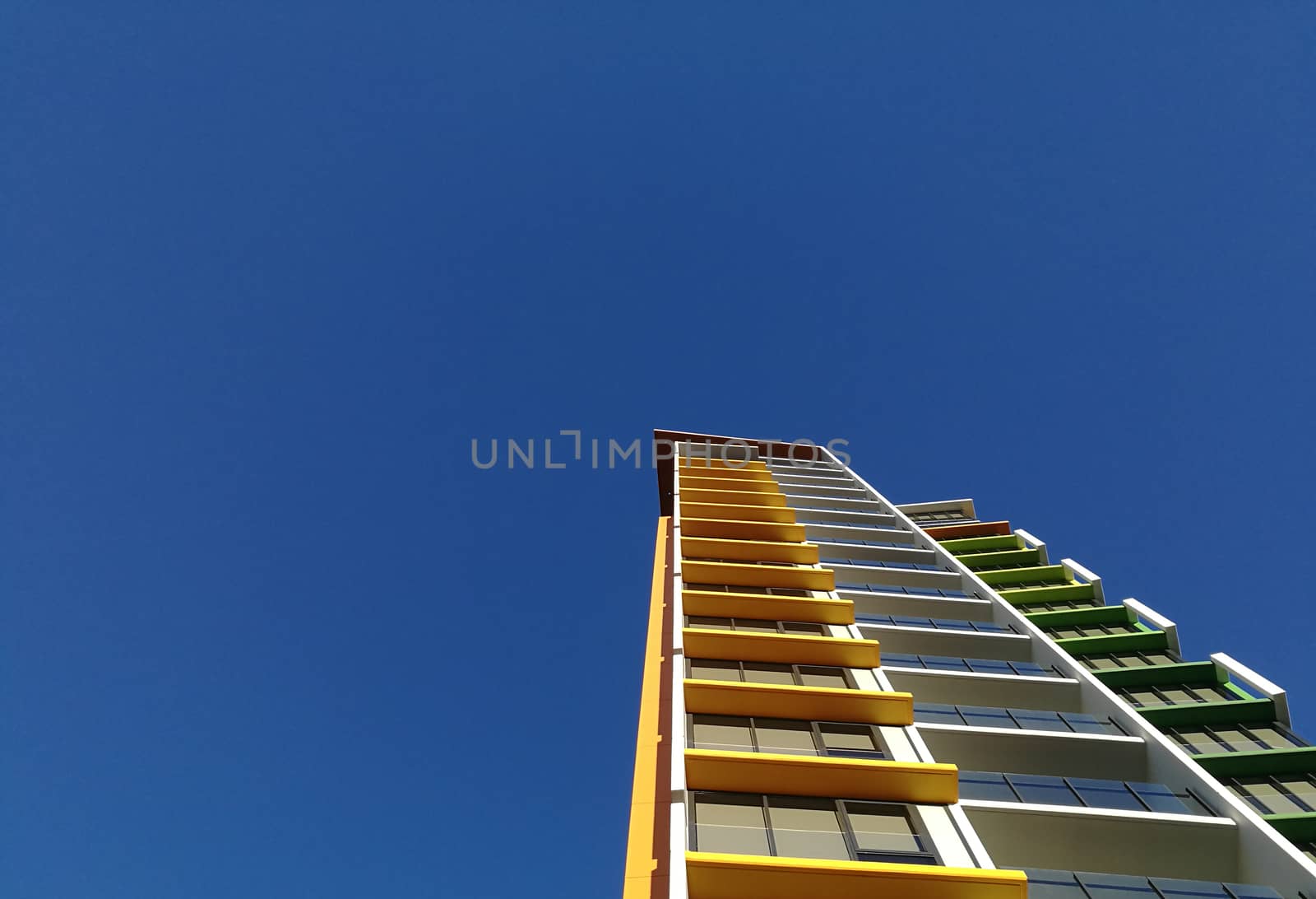 Modern high rise yellow apartment and blue sky by eyeofpaul