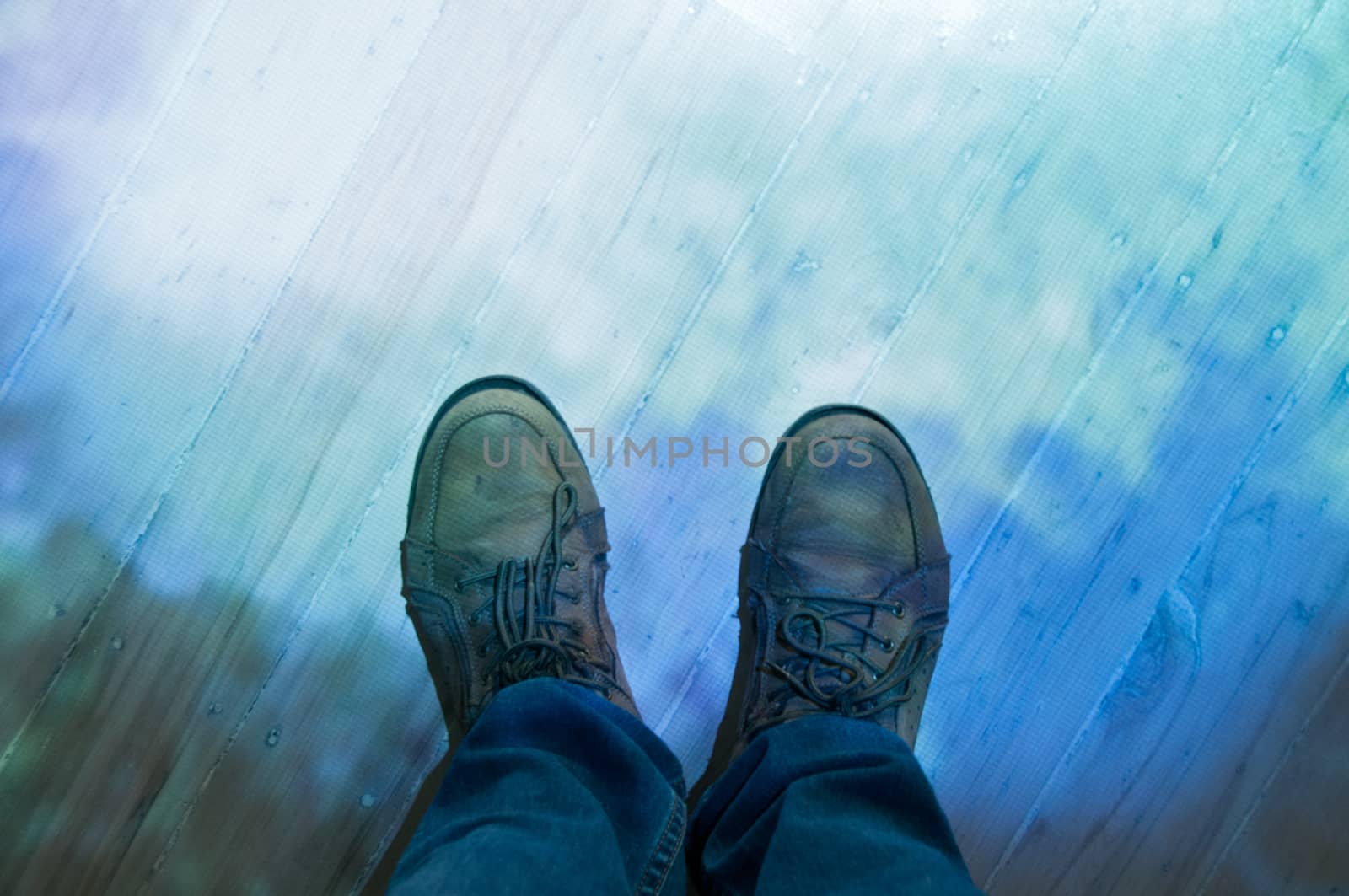 Brown leather shoes and blue jeans standing on a floor by eyeofpaul