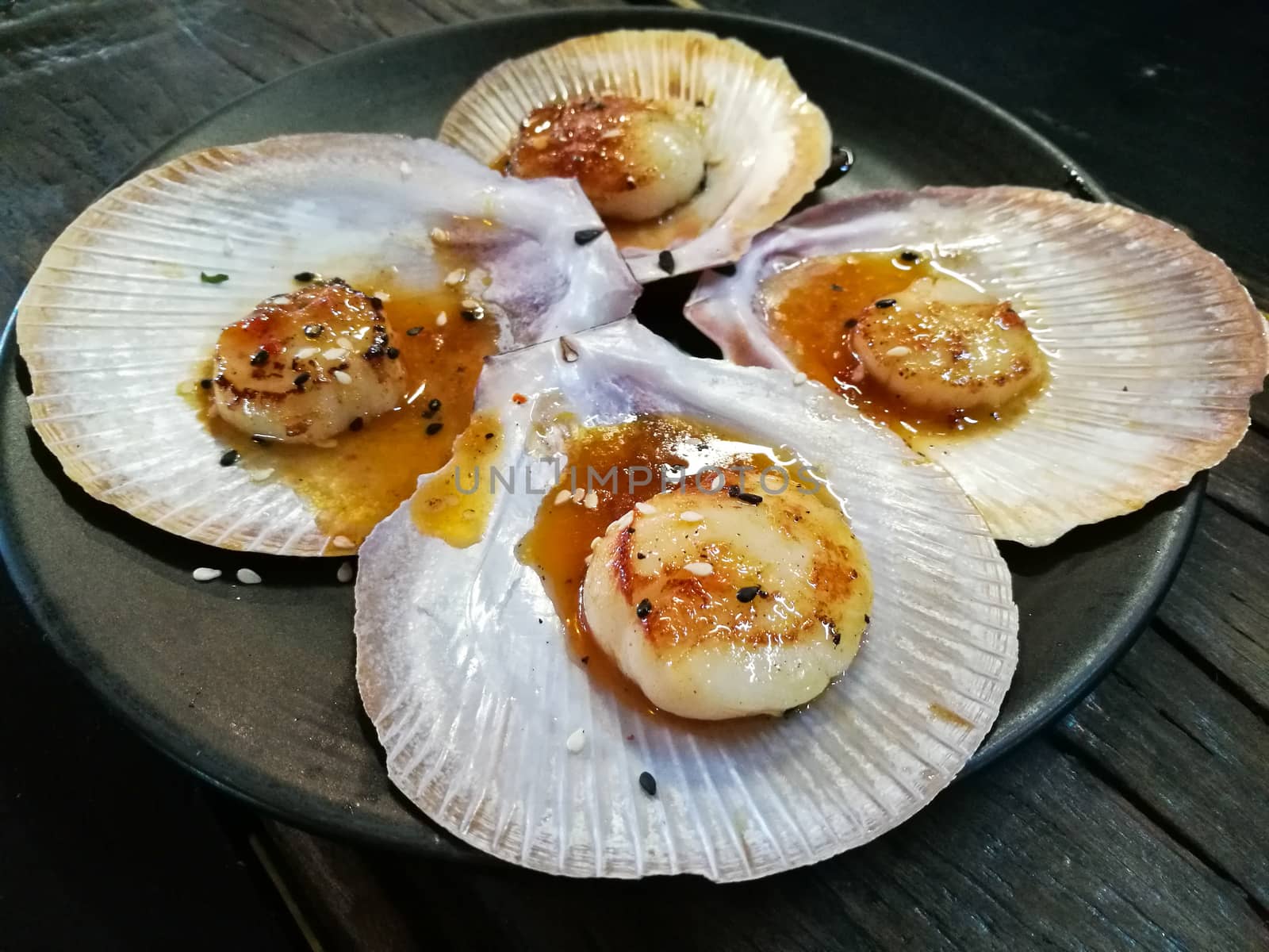 Giant grilled fresh Tasmanian scallops with fresh butter on black plate