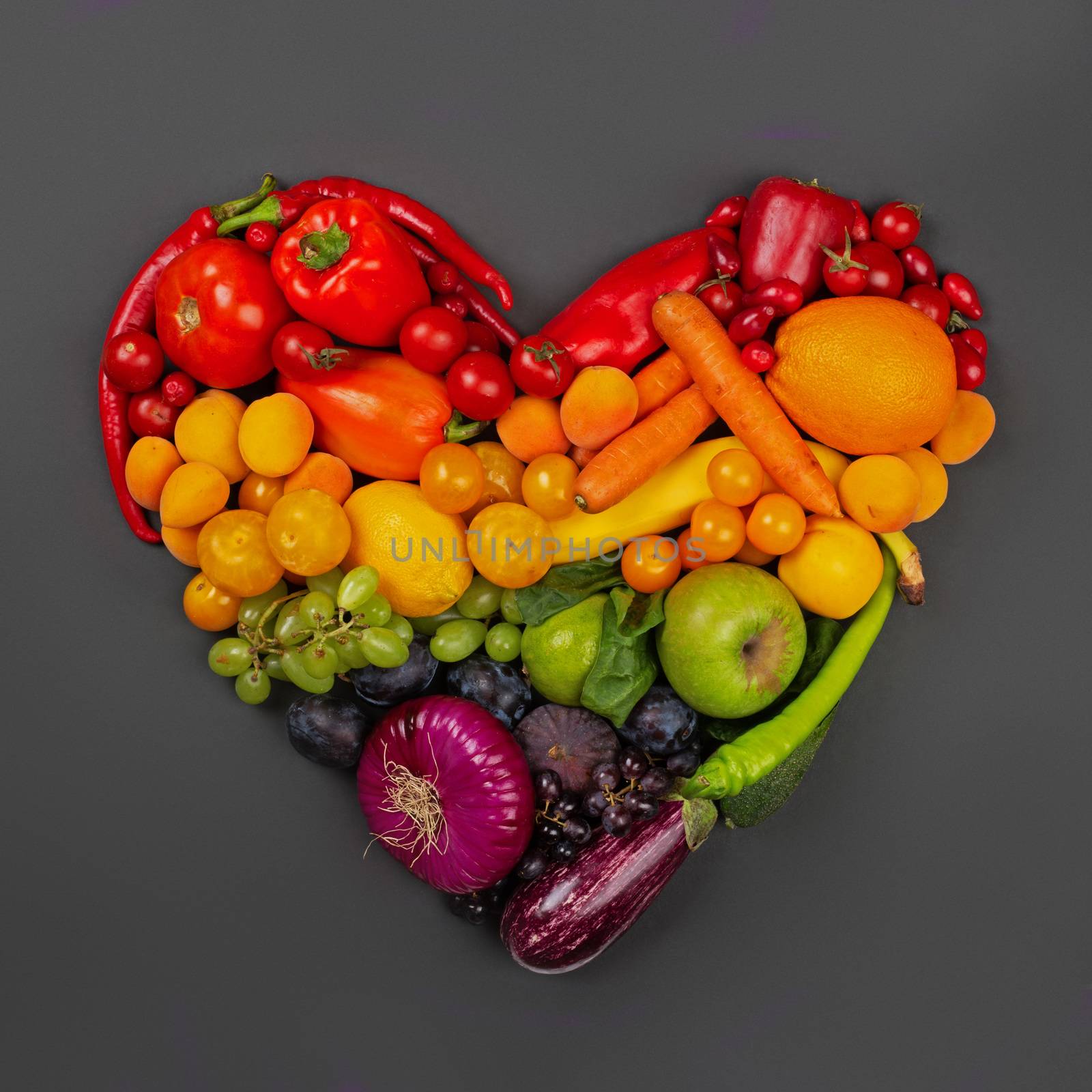 Rainbow heart of fruits and vegetables on gray background go vegetarian love healthy eating concept