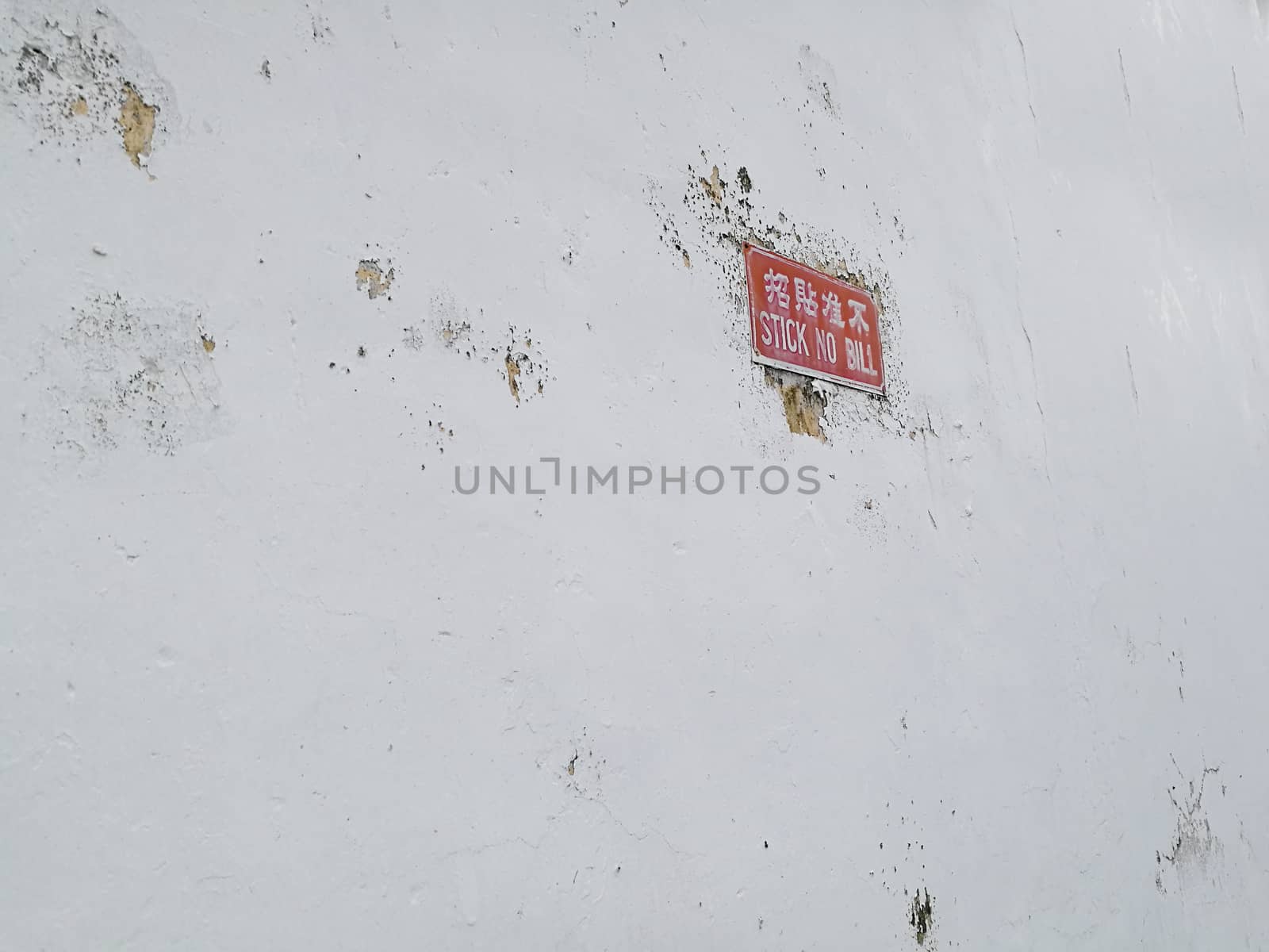 White concrete wall with red stick no bill post sign