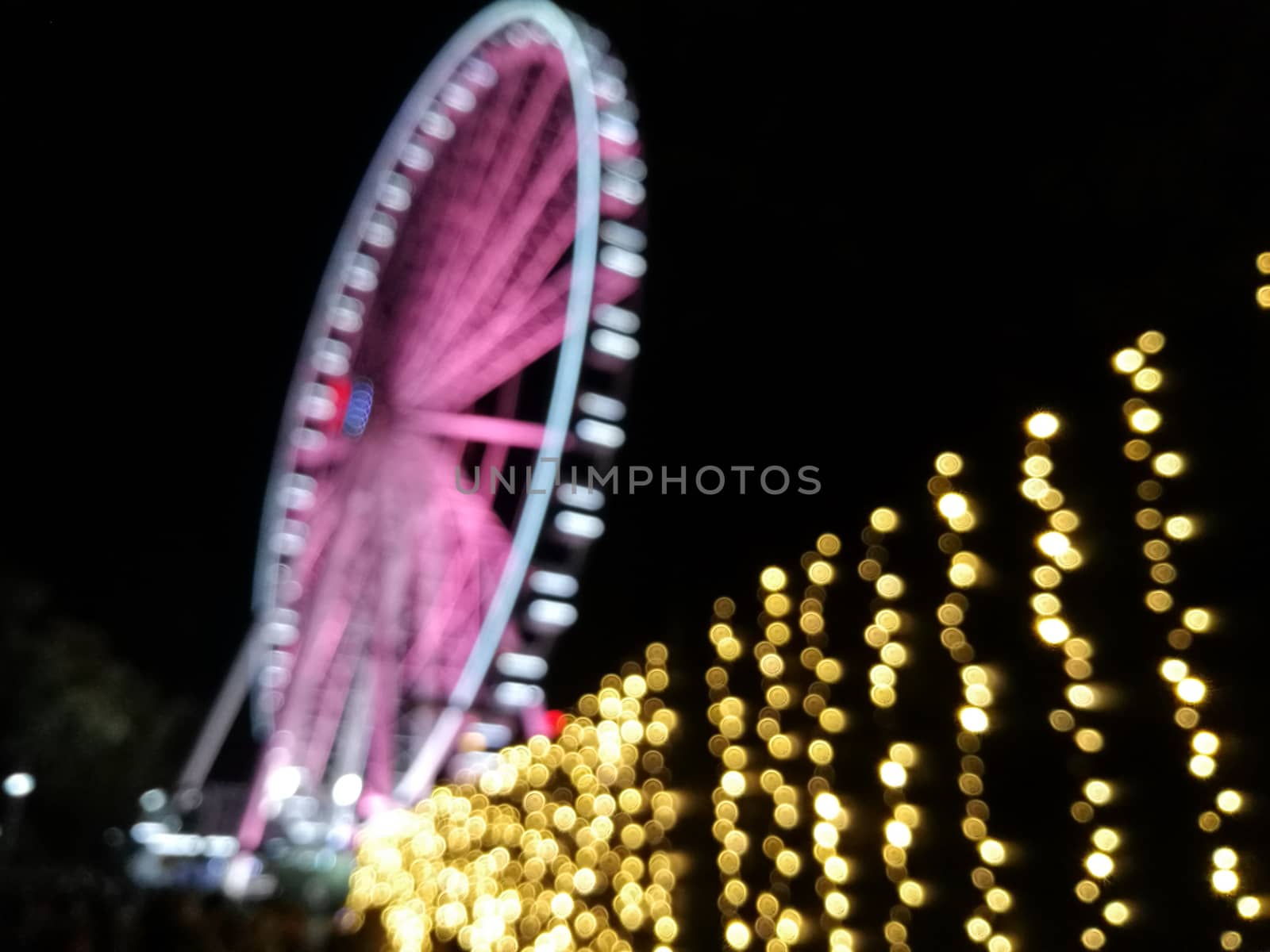 Defocused scene of giant pink flyer ferris wheel at night with y by eyeofpaul