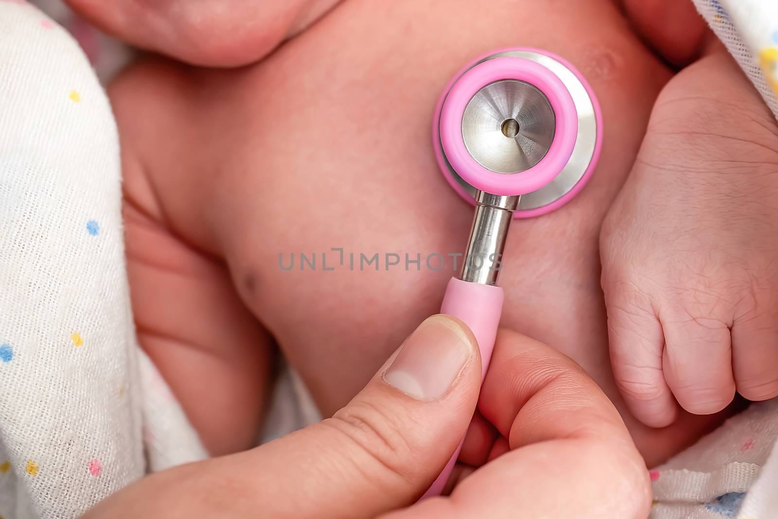 A nurse using a stethoscope to examine a newborn baby's heart