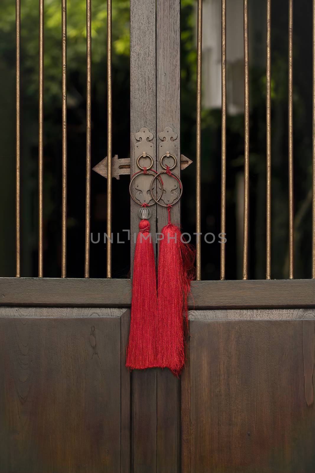 A chinese style wooden door panels with metal rails and intricate ring door handles.