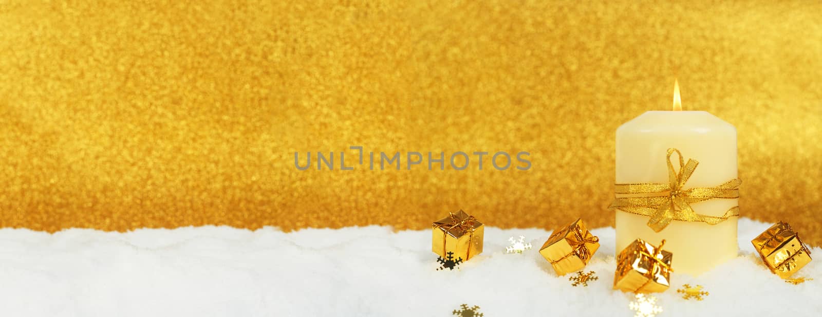 Christmas candle with golden christmas decor in the snow on glitter background